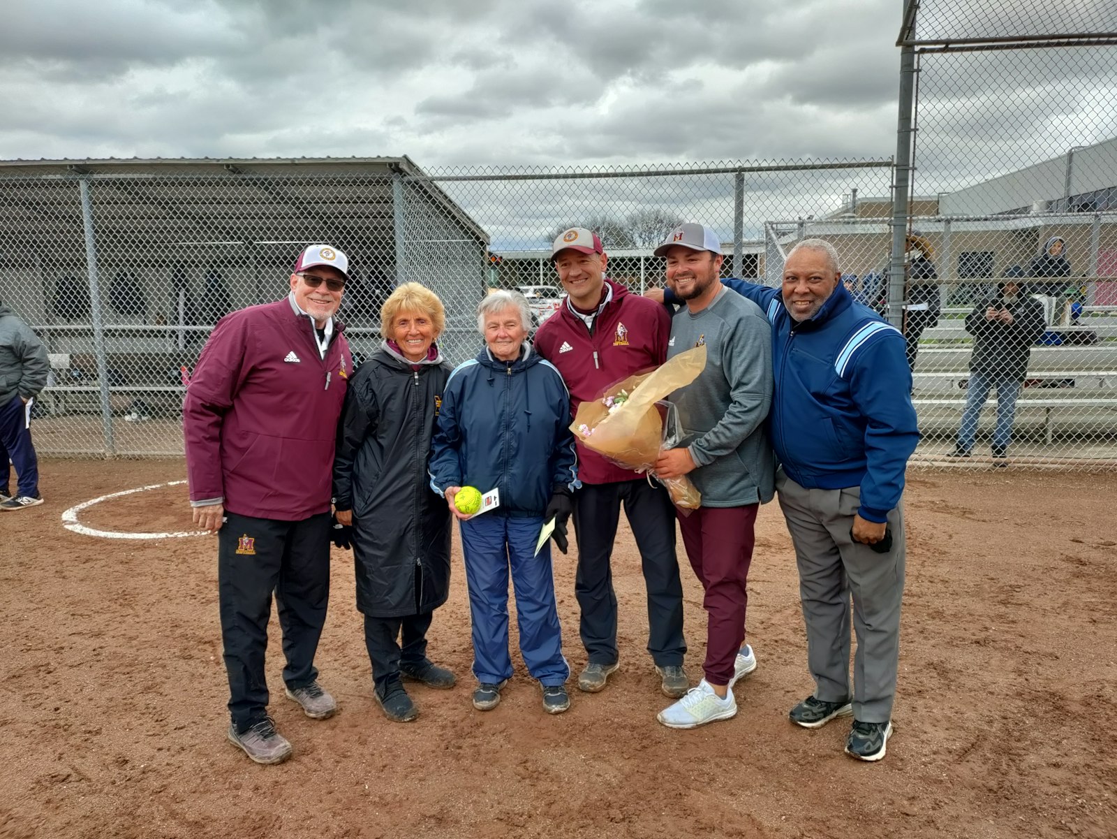 Regina’s legendary athletic director Diane Laffey (in blue jacket) was honored by Mercy officials marking her retirement this spring after 60 years. Participating in the tribute were Jerry Ashe (left), Mercy assistant softball coach, Nancy Malinowski, who retired last year after 42 years as Mercy AD, Mercy softball coach Corey Burras, Mercy AD Brandon Malinowski, and CHSL Hall of Fame umpire Jim Briggs.