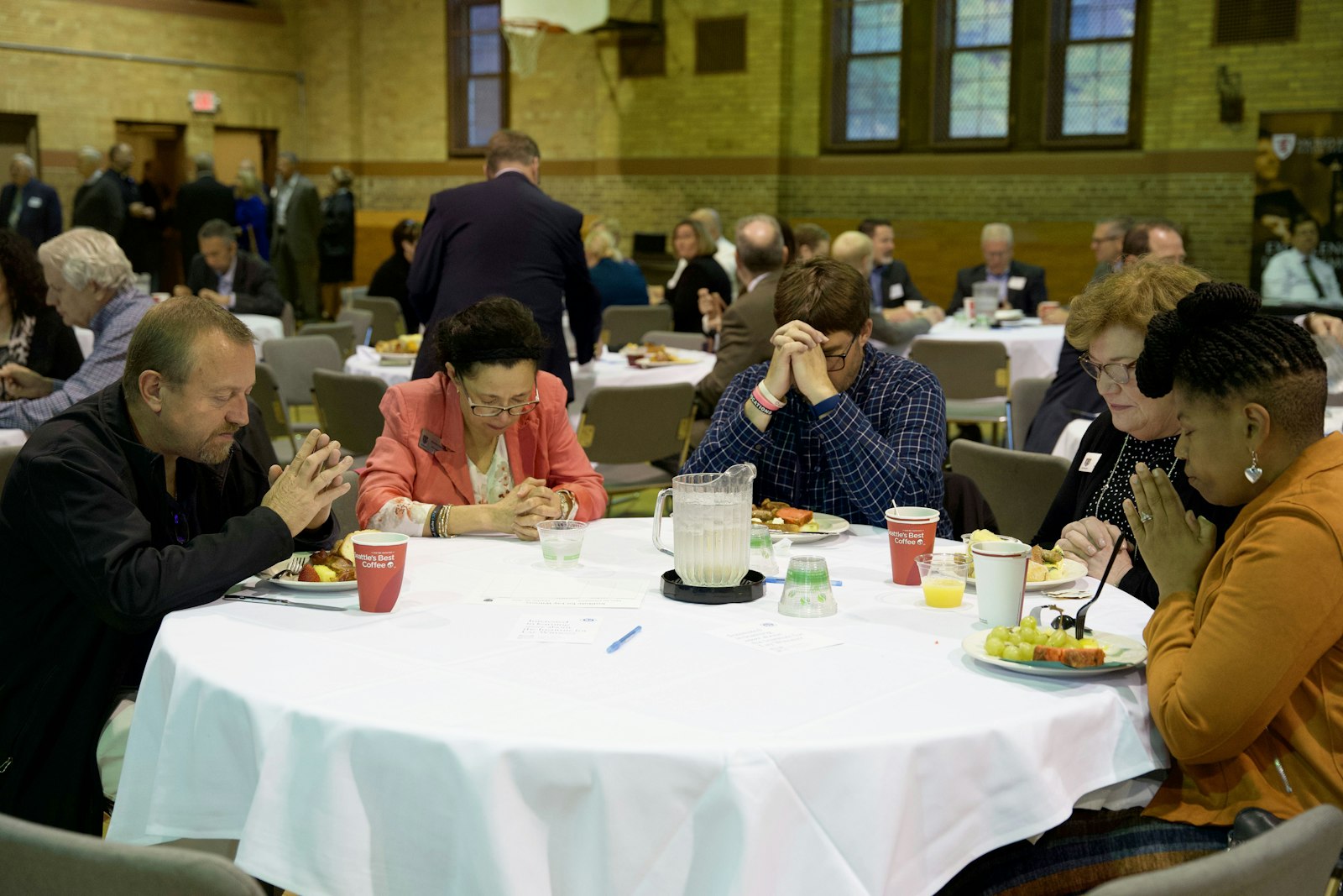 Catholic professionals pray together during a luncheon following the Mass in Sacred Heart's gym. Despite the pressures facing businesses, from inflation to employment, the Catholic faith grounds decisions in the dignity of the human person, Bishop Fisher said.