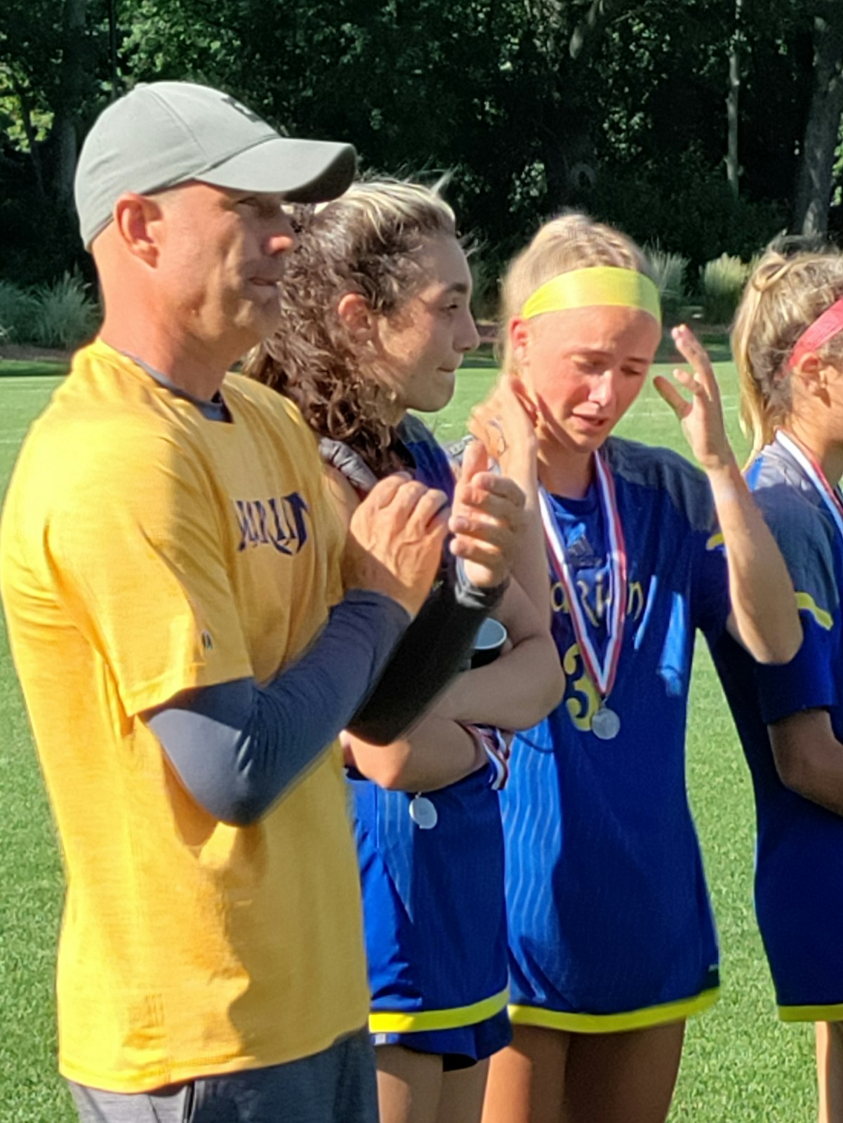 Birmingham Marian coach Reid Friedrichs, Angelina Briggs and Lucy Kinna share an emotional moment in the awards line after the Mustangs’ 2-1 loss to Grand Rapids Forest Hills Central. (Don Horkey | Special to Detroit Catholic)