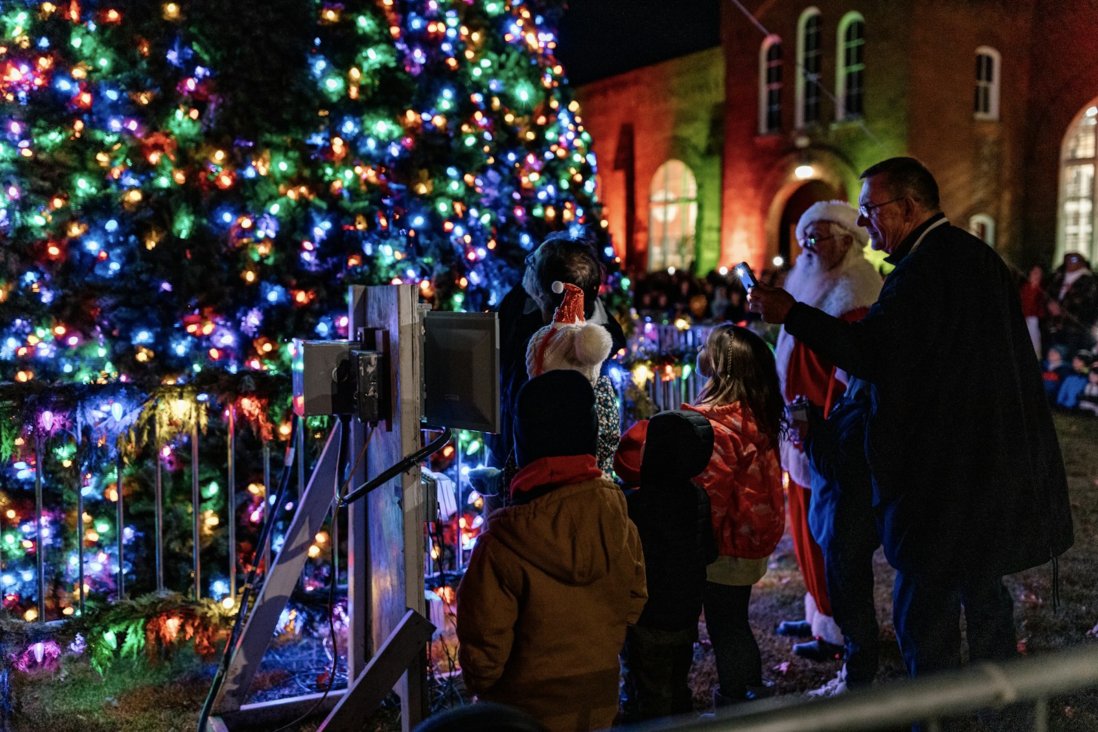 A family with small children gazes in wonder at the nearly 30-foot Christmas tree after flipping the switch to turn it on during the Orchard Lake Schools' "Mingle All the Way" celebration Nov. 19. (Alissa Tuttle | Special to Detroit Catholic)