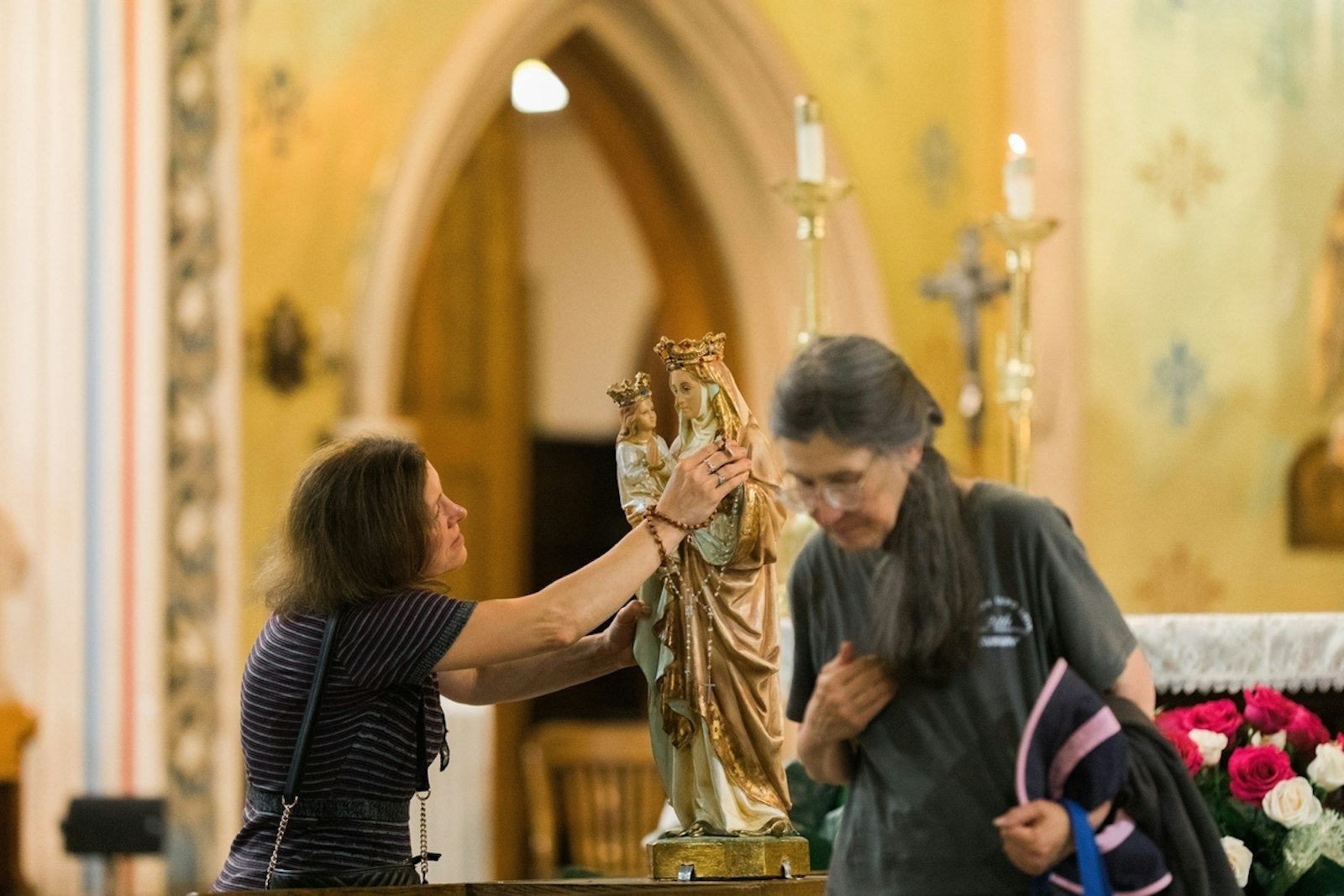 A pilgrim venerates a statue of St. Anne, the grandmother of Jesus, during the parish's patronal feast day in 2019. The Basilica of Ste. Anne is home to a vibrant culture of faith, but decades of wear and tear on the aging church have resulted in a need for millions of dollars in restoration. This funding will be fully covered through the parish's partnership with The Catholic Initiative. (Photo by Naomi Vrazo | Detroit Catholic)