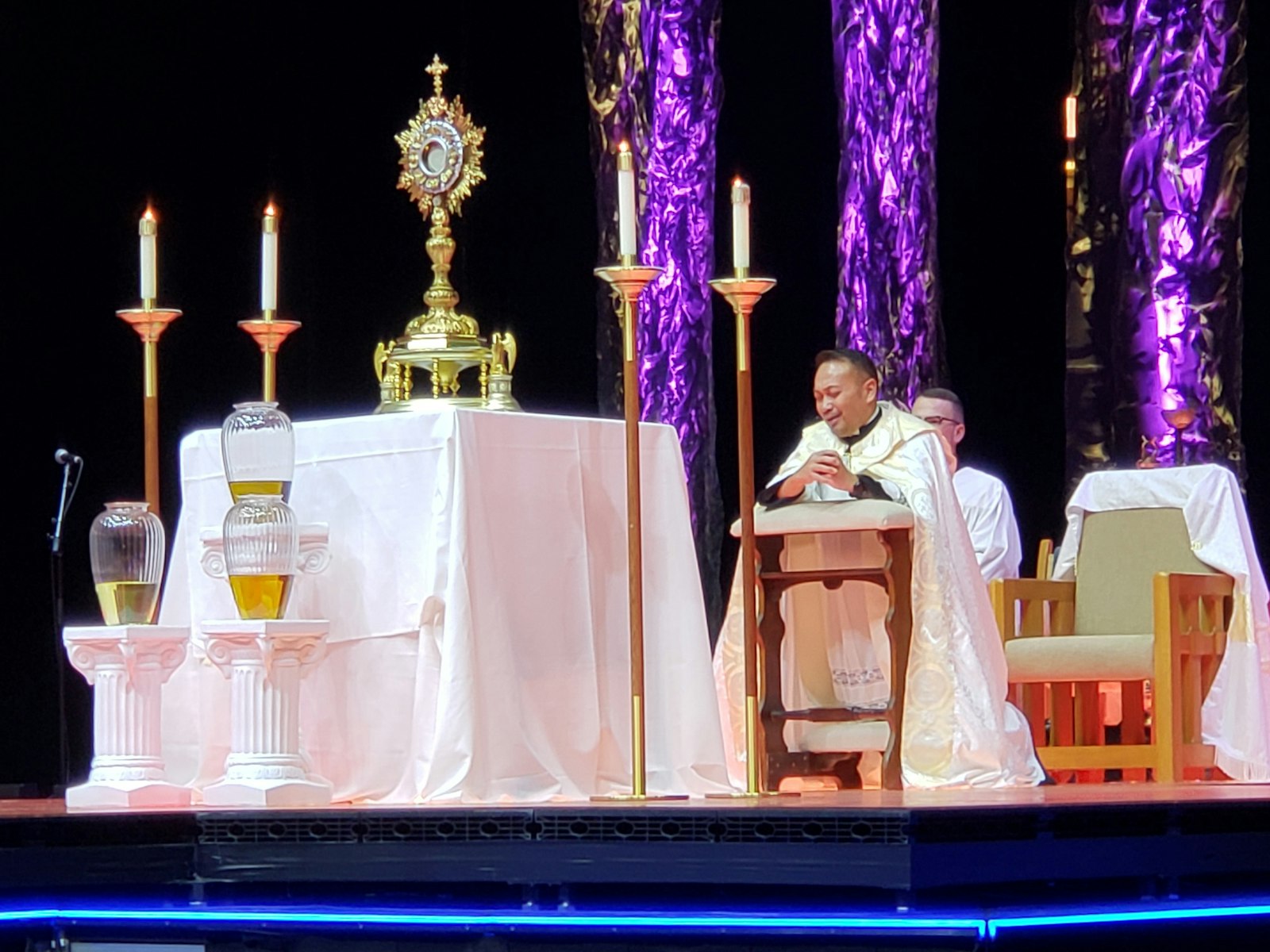 Father Leo Patalinghug speaks to the nearly 11,000 participants at the National Catholic Youth Conference while kneeling before the Blessed Sacrament during adoration at Lucas Oil Stadium in Indianapolis Nov. 19, 2021. (CNS photo/Natalie Hoefer, The Criterion)