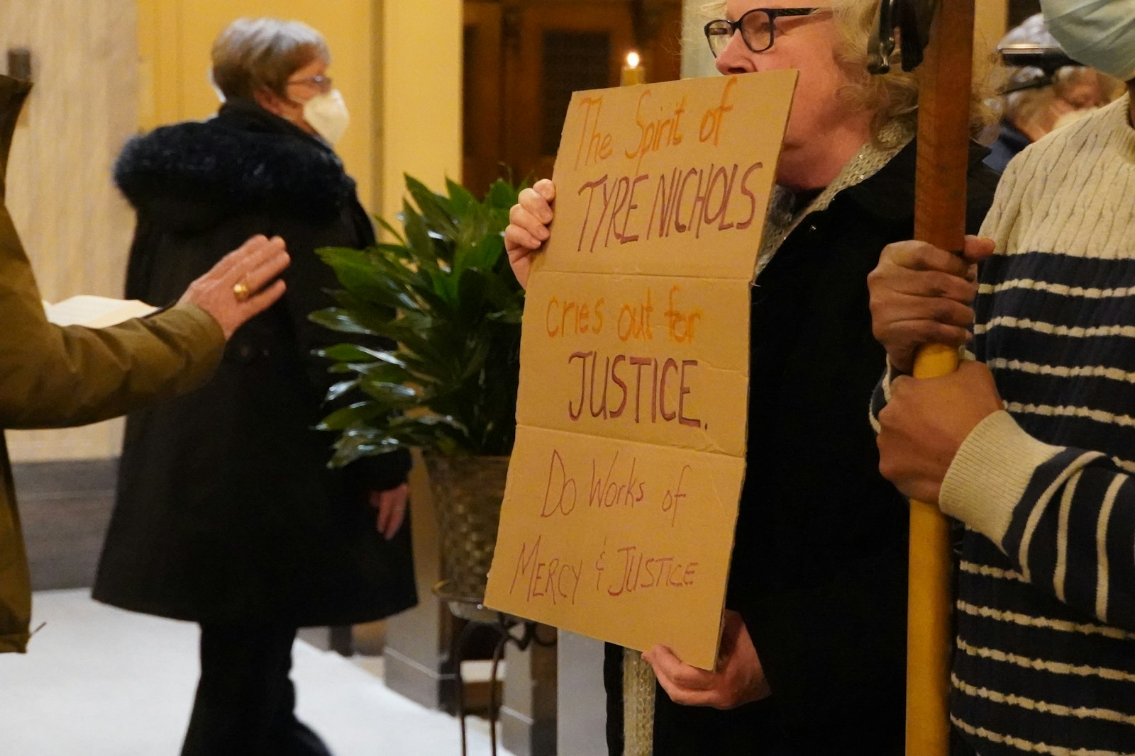 Un feligrés sostiene un cartel que dice: "El espíritu de Tire Nichols clama por justicia. Haz obras de misericordia y justicia".