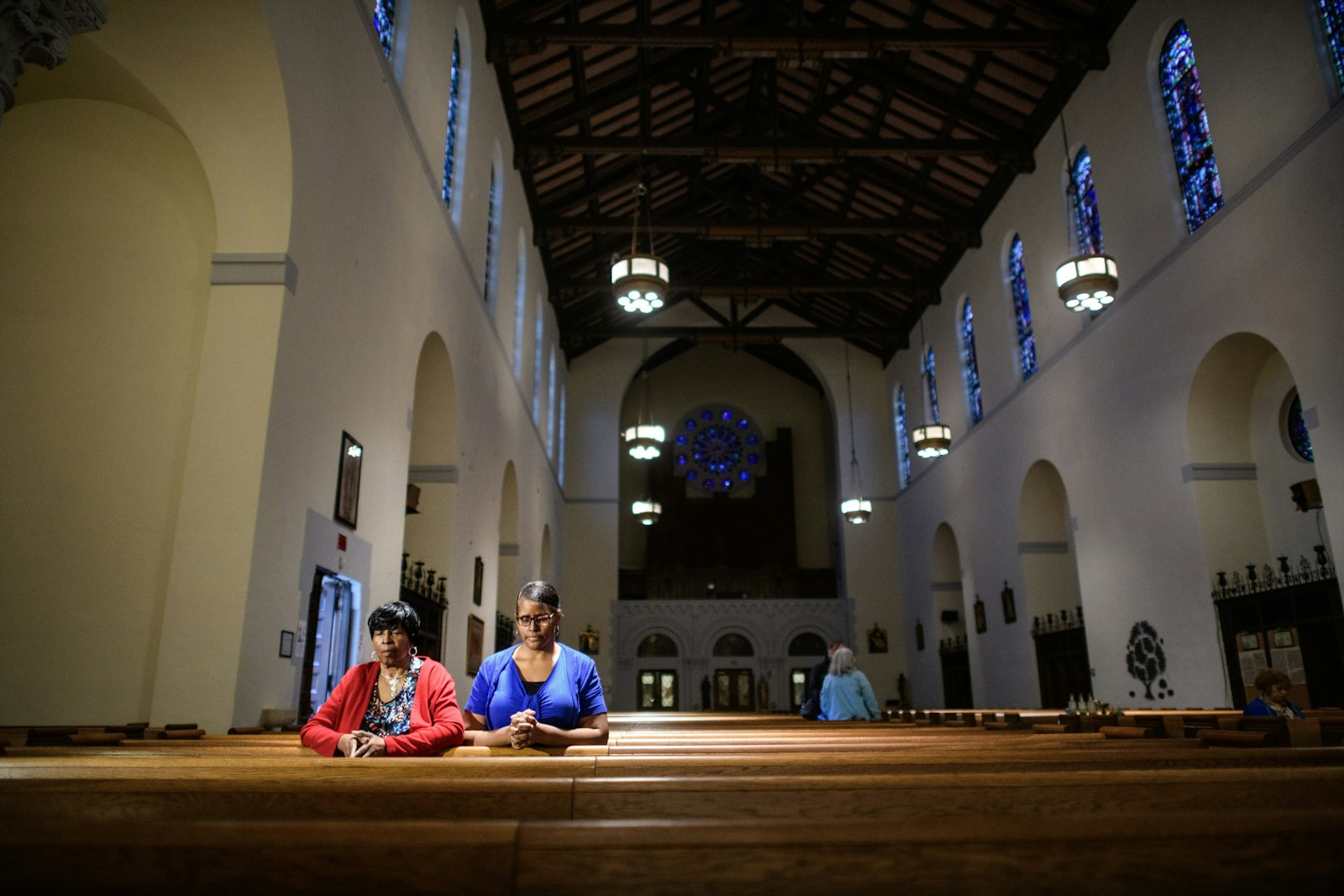 Two women pray inside St. Charles Lwanga Parish in this 2019 file photo. The historic parish offers critical services in its community, including a partnership with Ceciliaville, a nonprofit providing community programs and services, as well as an outlet to play basketball for Detroit youths.