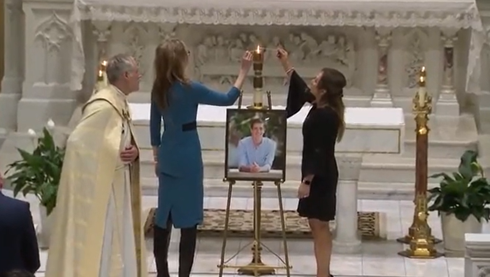 Members of St. Paul on the Lake Parish in Grosse Pointe Farms light candles in the sanctuary surrounding a picture of Brian Fraser, 20, a member of the parish who lost his life Feb. 13 during a shooting on the campus of Michigan State University. (Livestream video screengrab courtesy of WDIV, pool)