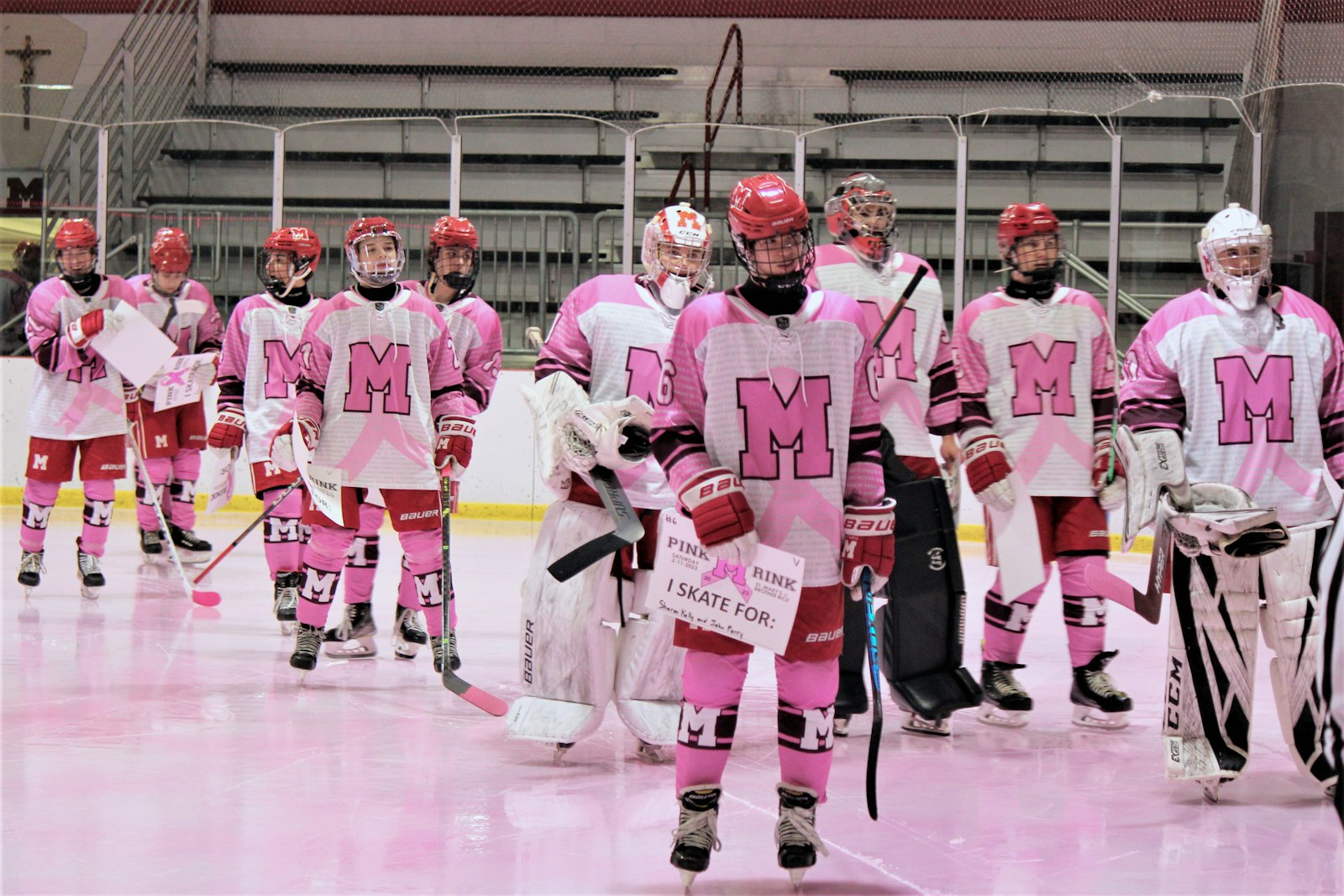 Sporting special uniforms, the Eaglets take to the ice – which was dyed pink – prior to the varsity game against Brother Rice.