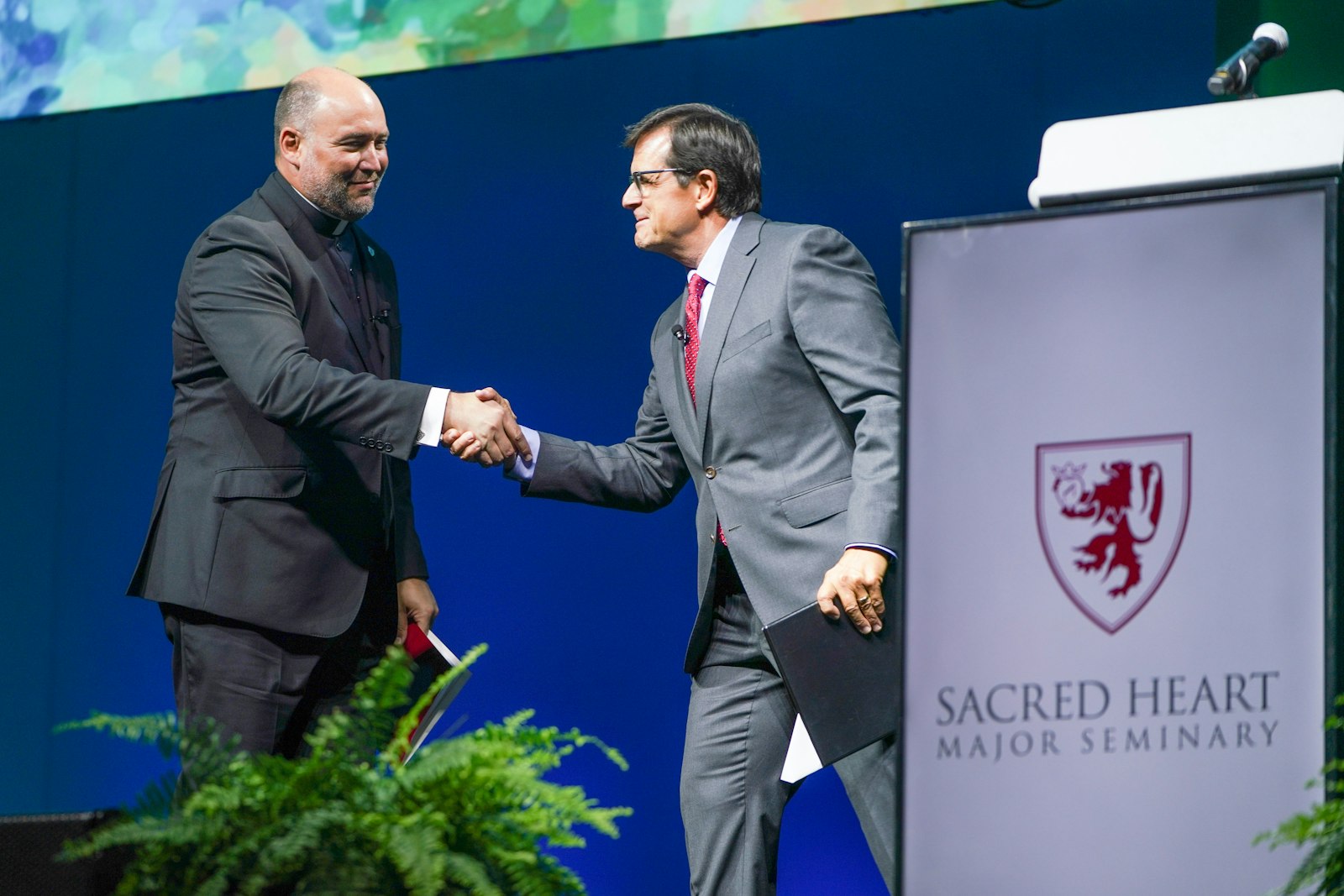 Chuck Gaidica, presentador y antiguo conductor de noticias del Canal 4, quien recientemente regresó a su fe católica de juventud, presenta al padre Stephen Burr, rector del Seminario Mayor del Sagrado Corazón, durante la Gala del Arzobispo el 8 de junio en Huntington Place.