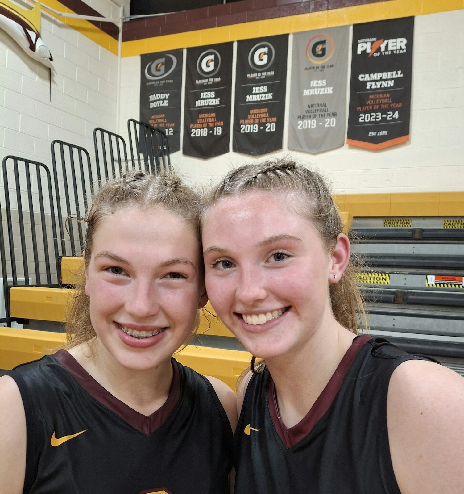 Sophomore outside hitter Kate Kalczynski, left, and senior setter Campbell Flynn combine to power Mercy’s offense. The banners in the background celebrate Flynn’s Michigan Player of the Year award in 2023 alongside similar banners for Maddy Doyle in 2011 and Jess Mruzik’s state and national POY honors in 2018 and 2019.