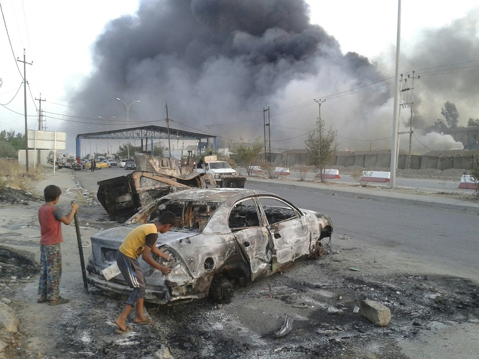 Children in northern Iraq stand next to a burned vehicle during clashes between ISIS and Iraqi security forces. This photo from 2014 mirrors the chaos described “Nazar’s Journey.” (Photo: Reuters via OSV News)