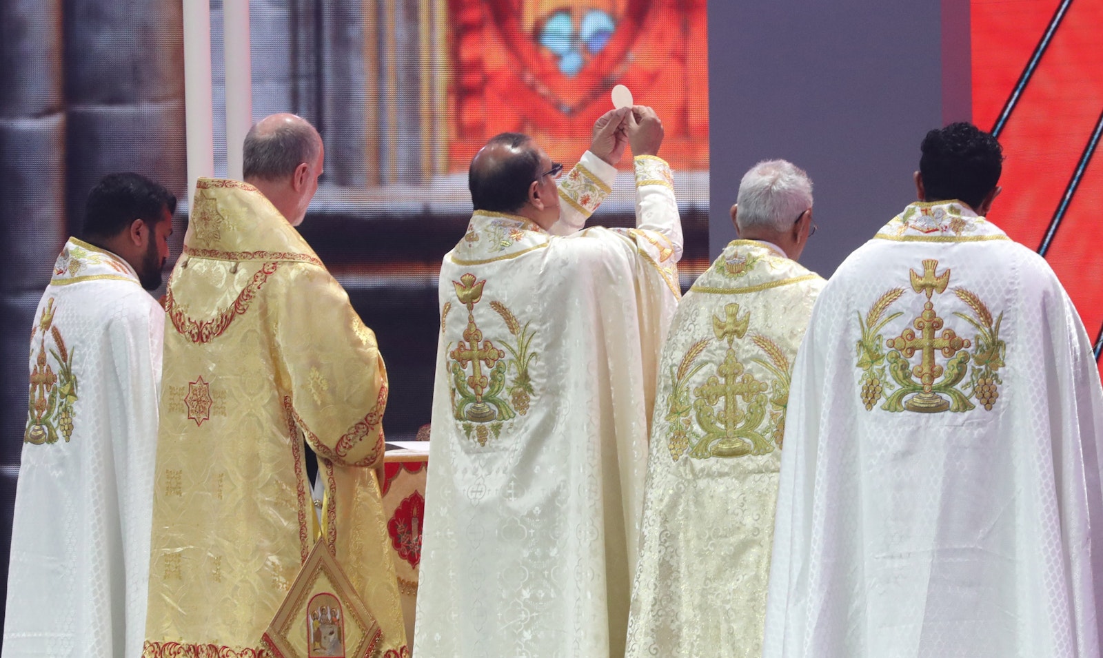 Syro-Malabar Bishop Joy Alappatt raises the host as he concelebrates Holy Qurbana with Archbishop Borys A. Gudziak of the Ukrainian Catholic Archeparchy of Philadelphia, in gold vestments, July 20, 2024, at Lucas Oil Stadium in Indianapolis during the National Eucharistic Congress. Holy Qurbana is the name for Mass in the Catholic Church's Syro-Malabar rite. (OSV News photo/Bob Roller)