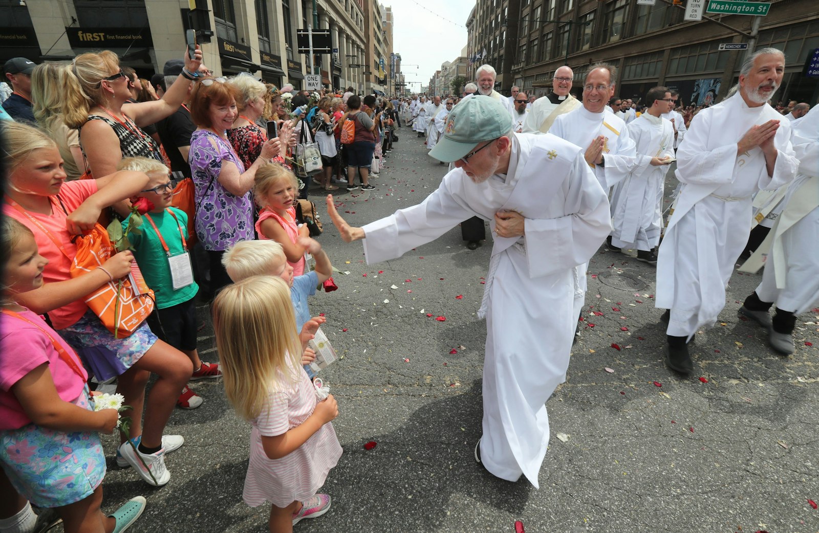 A clergyman gives children a high-five during the final Eucharistic procession of the National Eucharistic Congress in downtown Indianapolis July 20, 2024. (OSV News photo/Bob Roller)