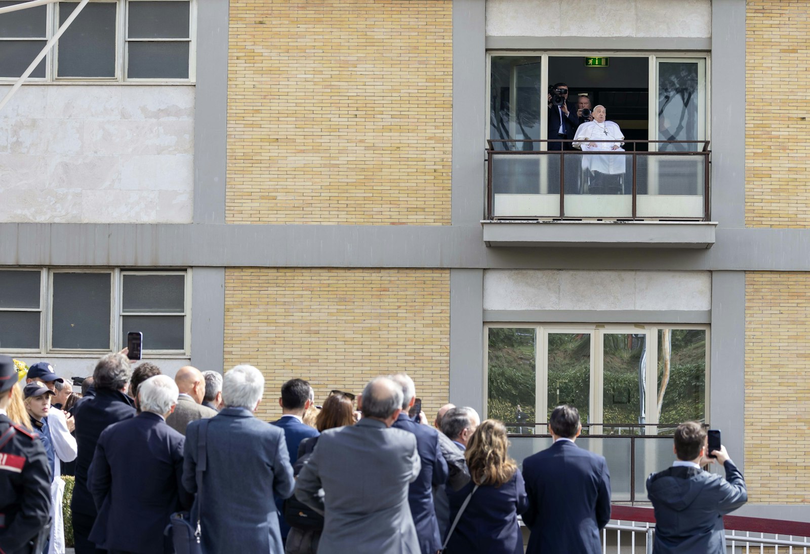 People watch and take photos as Pope Francis waves to a crowd of well-wishers at Rome's Gemelli hospital before returning to the Vatican March 23, 2025, after 38 days of treatment at the hospital. (CNS photo/Pablo Esparza)