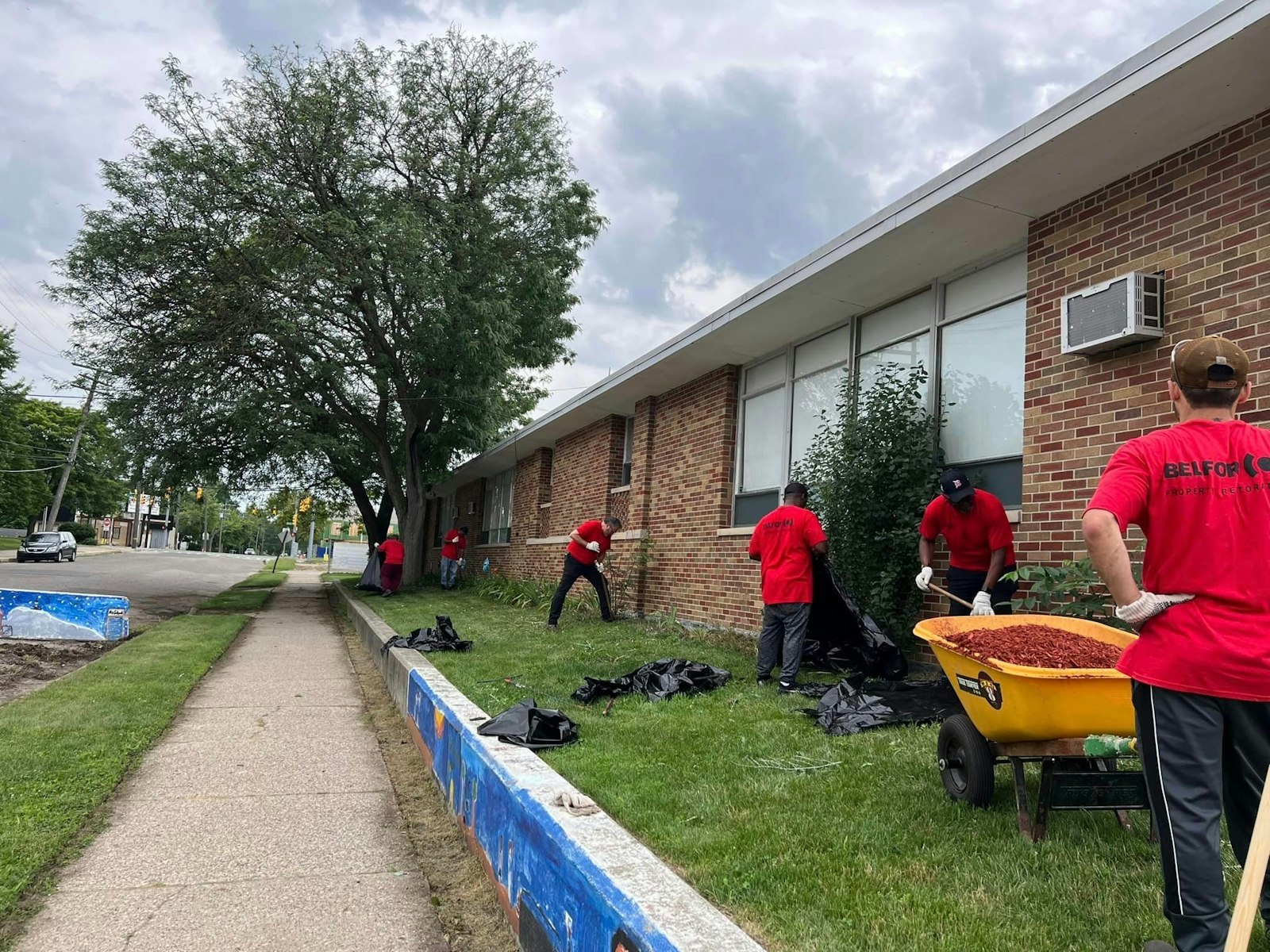 A cohort of men do landscaping at Christ the King Catholic School in Detroit in July. Thanks to Better Way Detroit, the school's exterior has a new look for the start of the academic year. (Courtesy of Better Way Detroit)