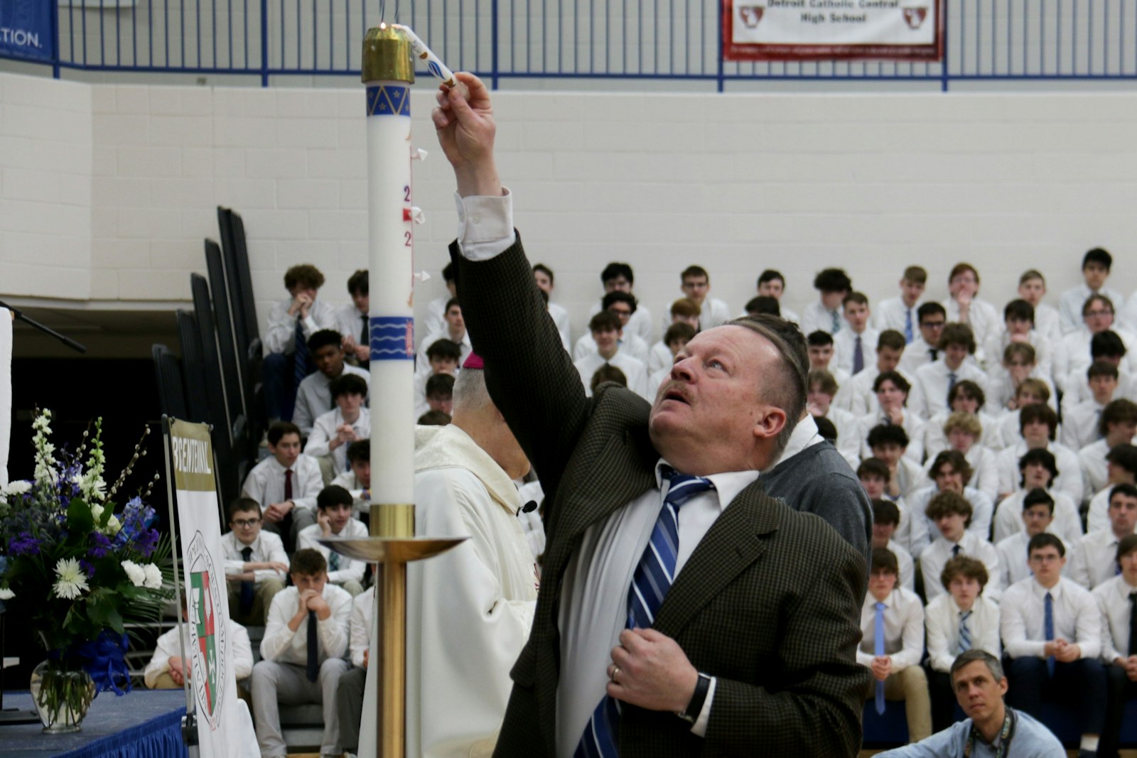 Paul Stuligross, a theology teacher at St. Mary's Preparatory School in Orchard Lake, lights the Easter candle during the Mass at Catholic Central. Stuligross said that theology class is a perfect place to meet students where they are in their faith.