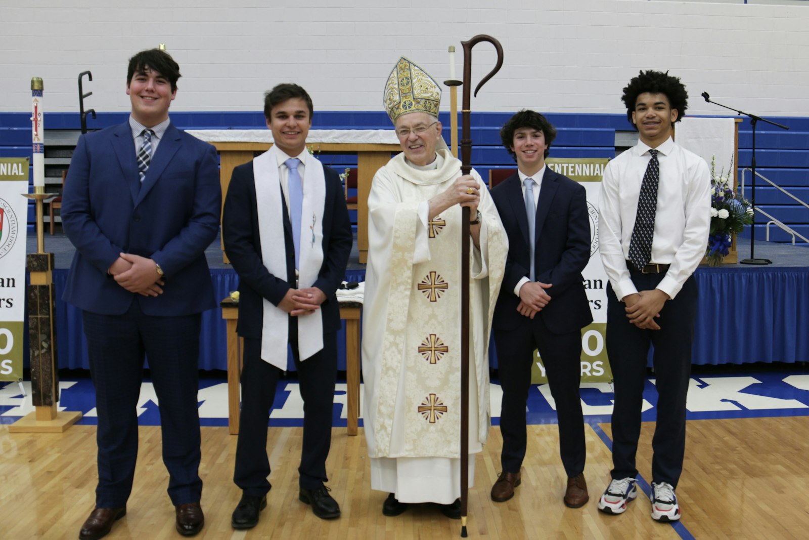 From left to right, Hayden Keeley, Dylan Magdich, Auxiliary Bishop Donald F. Hanchon, Nick Lopez and Chas Lewless pose for a picture after Bishop Hanchon confirmed all four and baptized Magdich during an April 27 all-school Mass..
