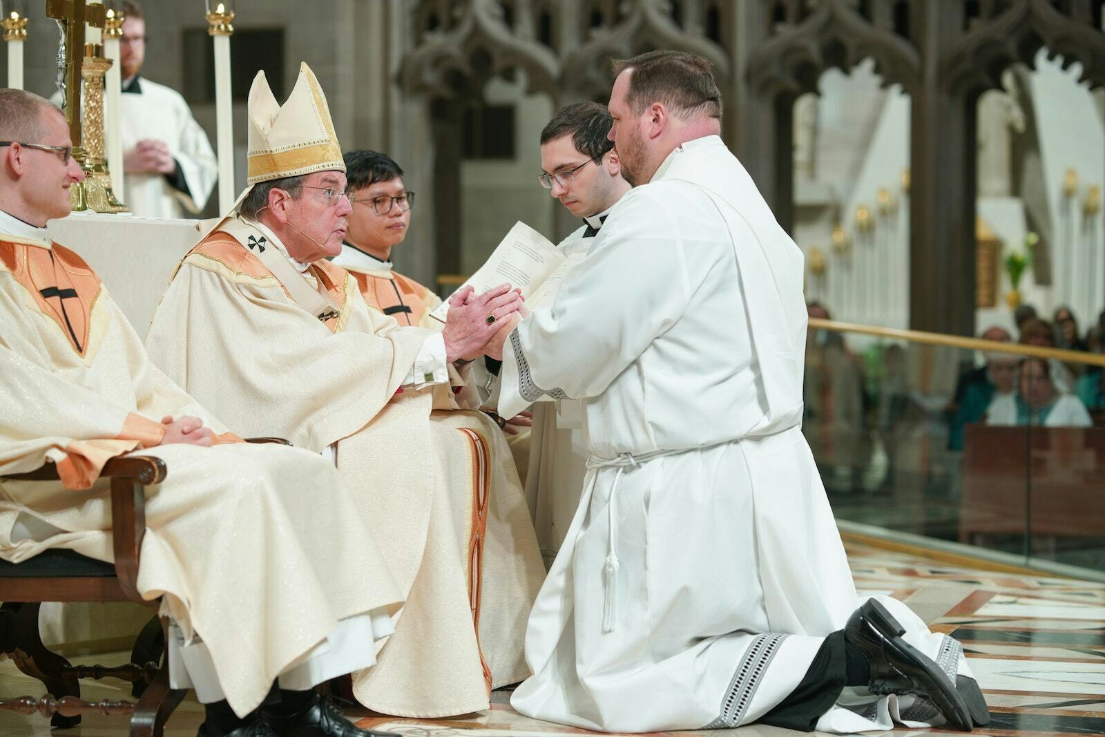 El padre Andrew Smith se arrodilla ante el Arzobispo Allen H. Vigneron y profiere su Promesa de Obediencia durante el Rito de Ordenación al Sacerdocio el 27 de mayo en la Catedral del Santísimo Sacramento.