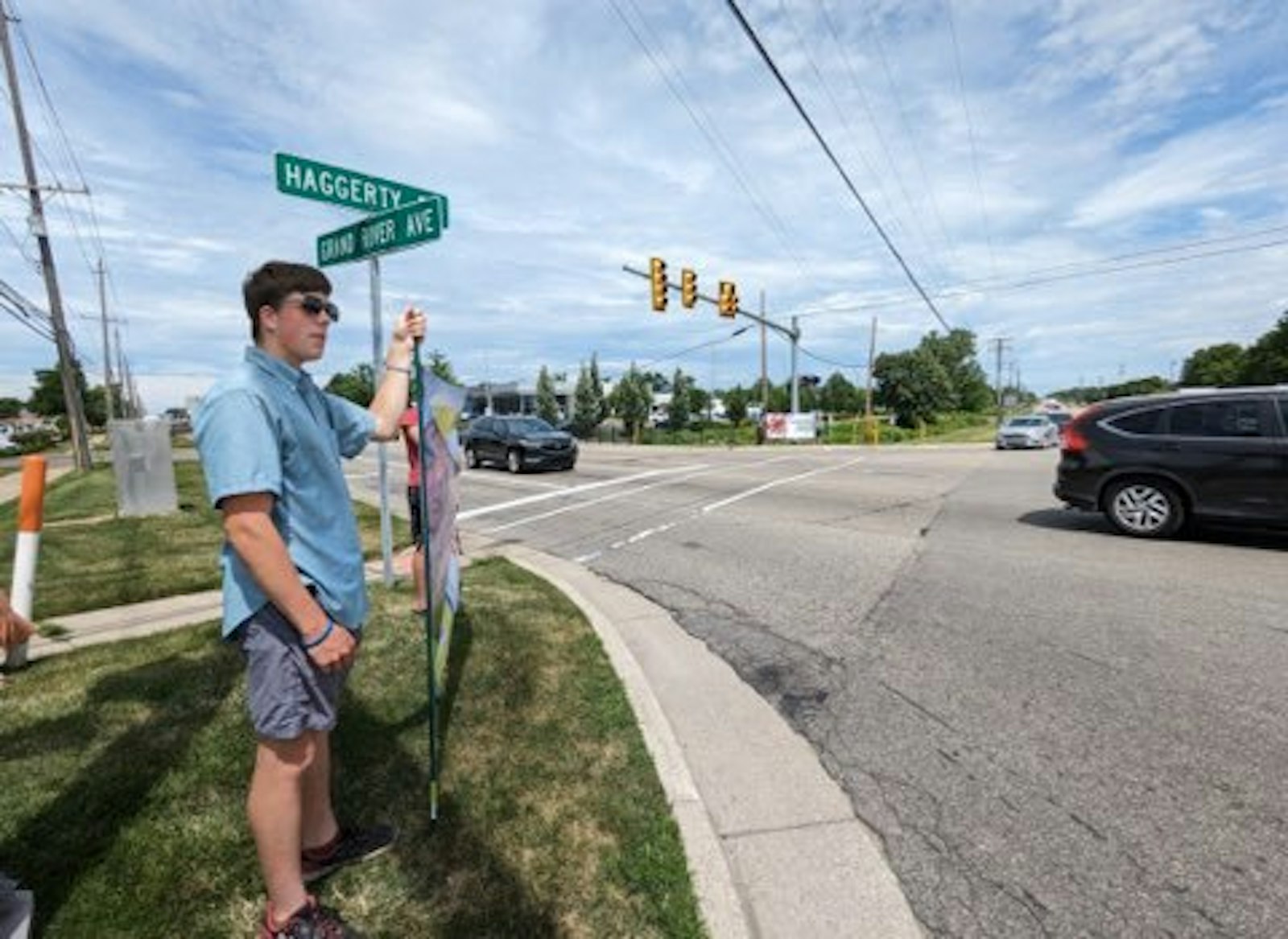 A young person holds a sign on a street corner in the Novi area, part of Protect Life Michigan's first full-time summer internship program. The 22 young interns have used Holy Family Parish in Novi as their home base to rest, pray and come together for encouragement.