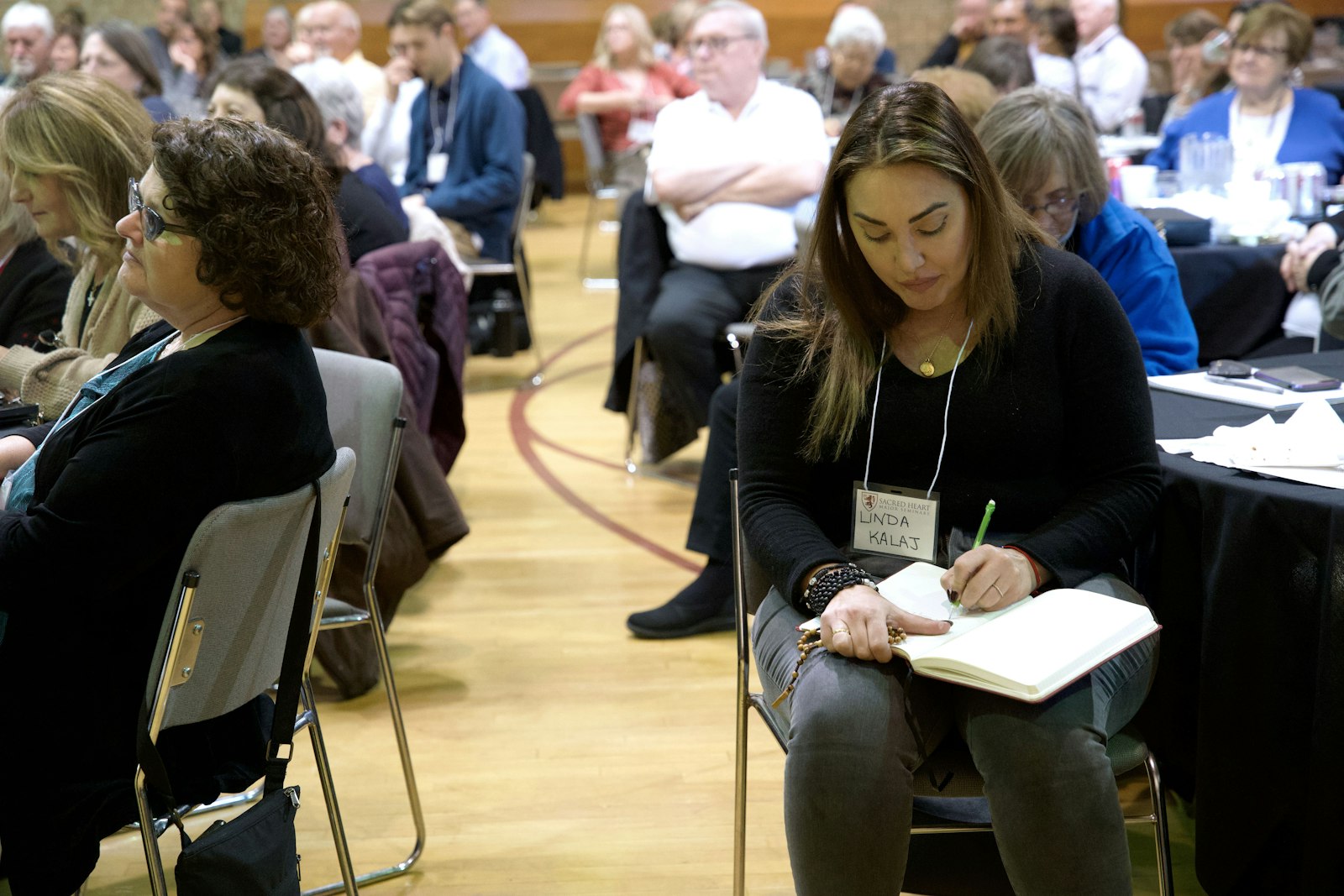 An attendee takes notes on Fr. Calloway's talk with her rosary in hand. Throughout history, Fr. Calloway said, the devil has tried to keep the rosary from the hands of the people of God, but it has persevered.