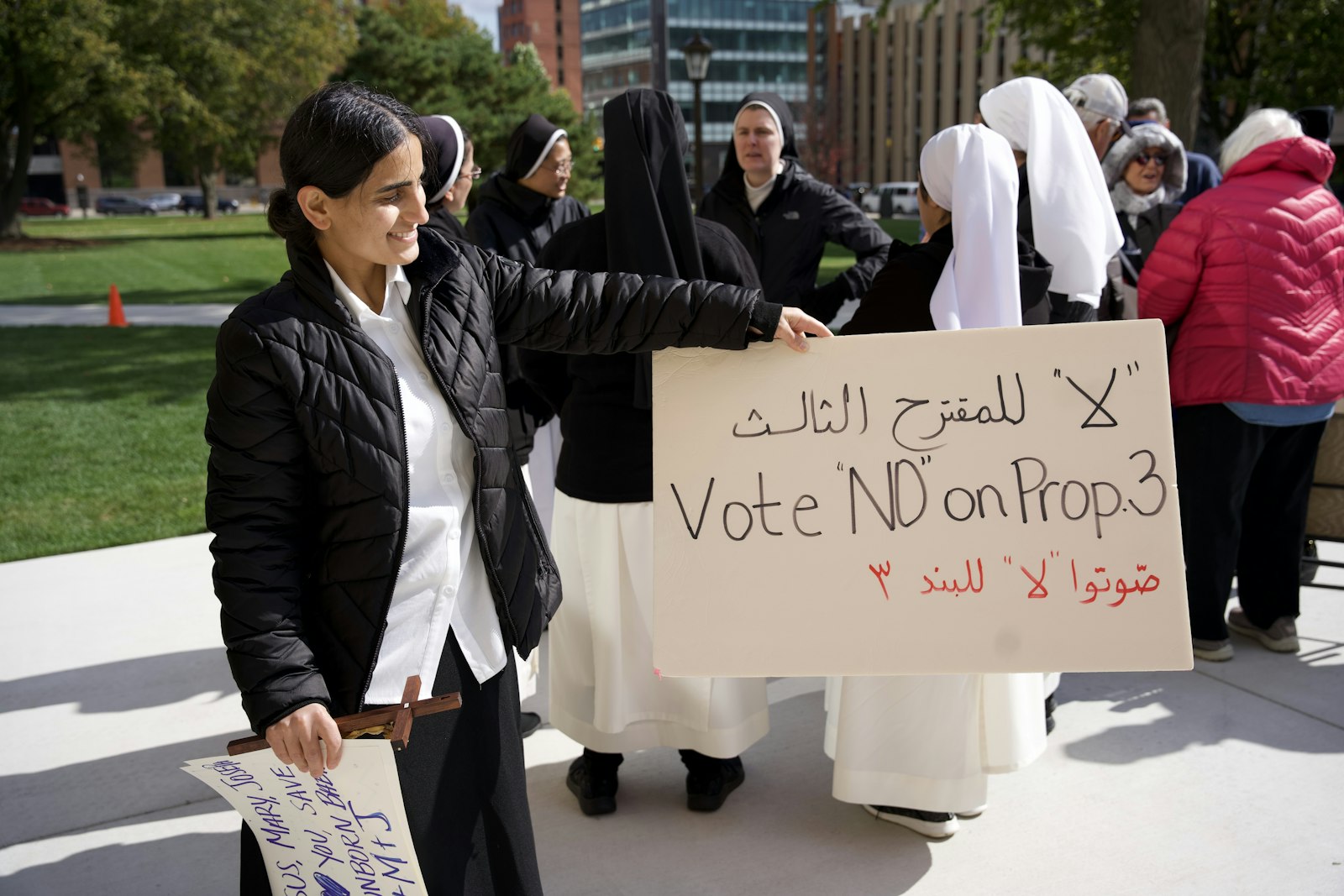 A Chaldean sister holds up a sign written in English and Arabic urging voters to reject Proposal 3.