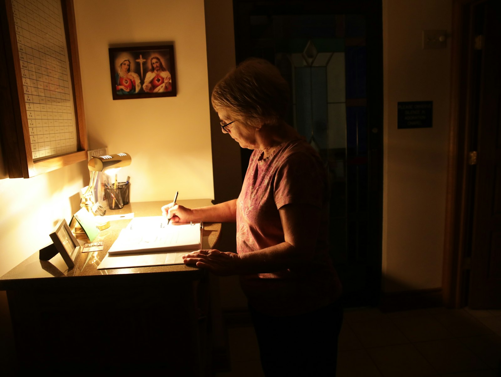 Karen Flint signs in to St. Charles Borromeo's adoration chapel for her time slot. Those who wish to make use of the chapel don't have to sign up -- anyone can just show up, she says -- but parishes do appreciate volunteers keeping vigil with the Lord.