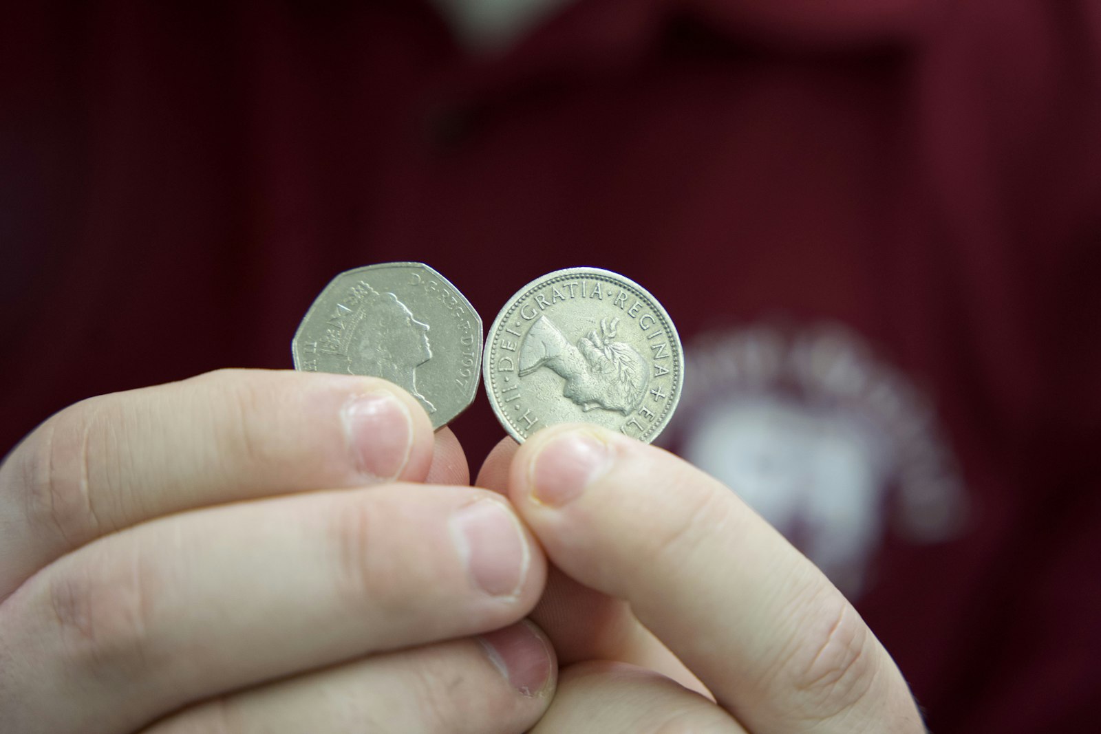 Rutkowski holds up British coins with Queen Elizabeth's image engraved on them, from his large collection of British money from over the course of her reign.