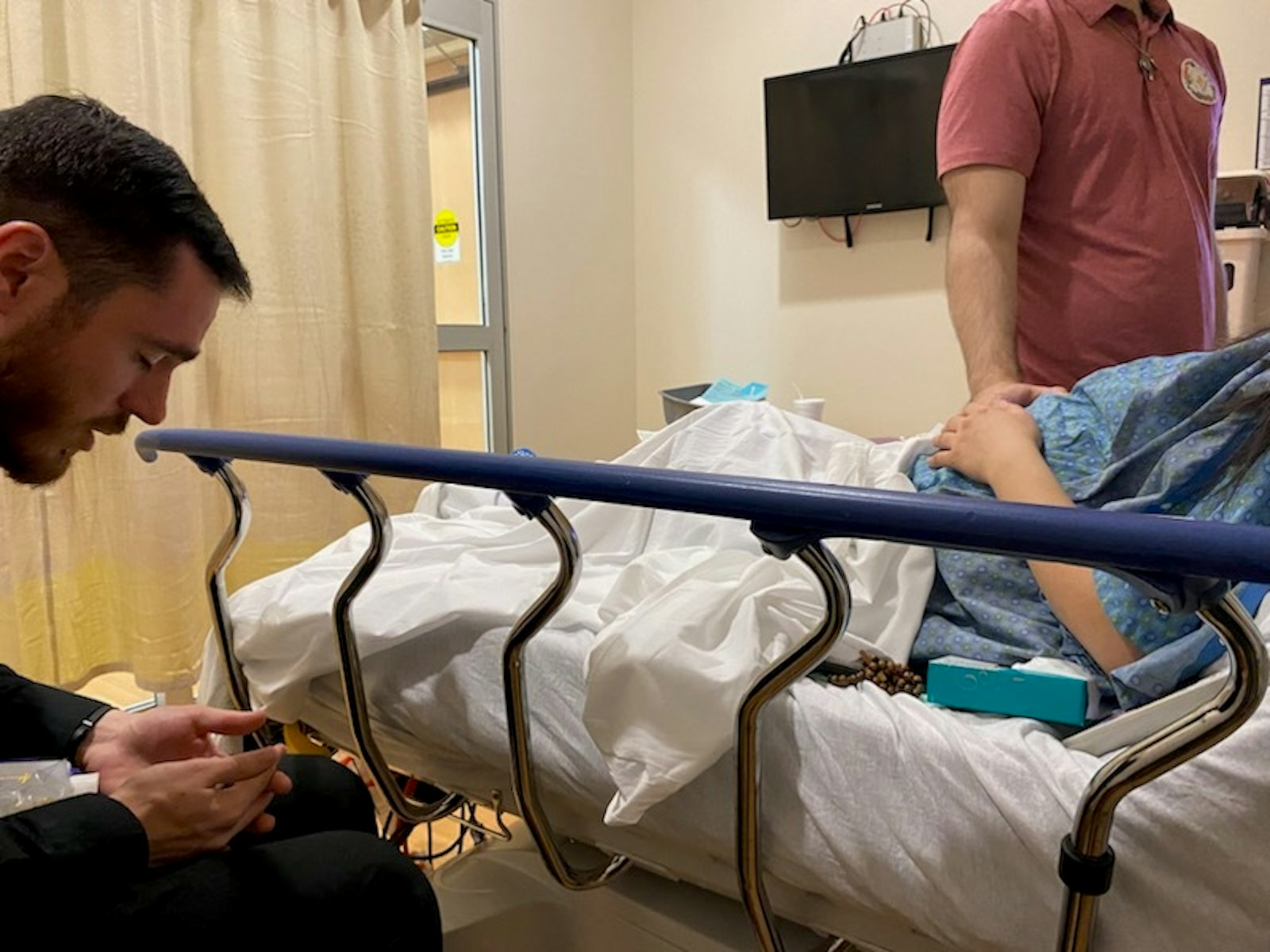 Fr. David Pellican, a priest of the Archdiocese of Detroit serving at the Church of the Divine Child in Dearborn, prays over Nicole LeBlanc shortly before the surgery. Fr. Pellican baptized the twins and gave them the sacrament of anointing, and has been at their parents' side throughout their difficult pregnancy. (Courtesy of Yanira Duque)