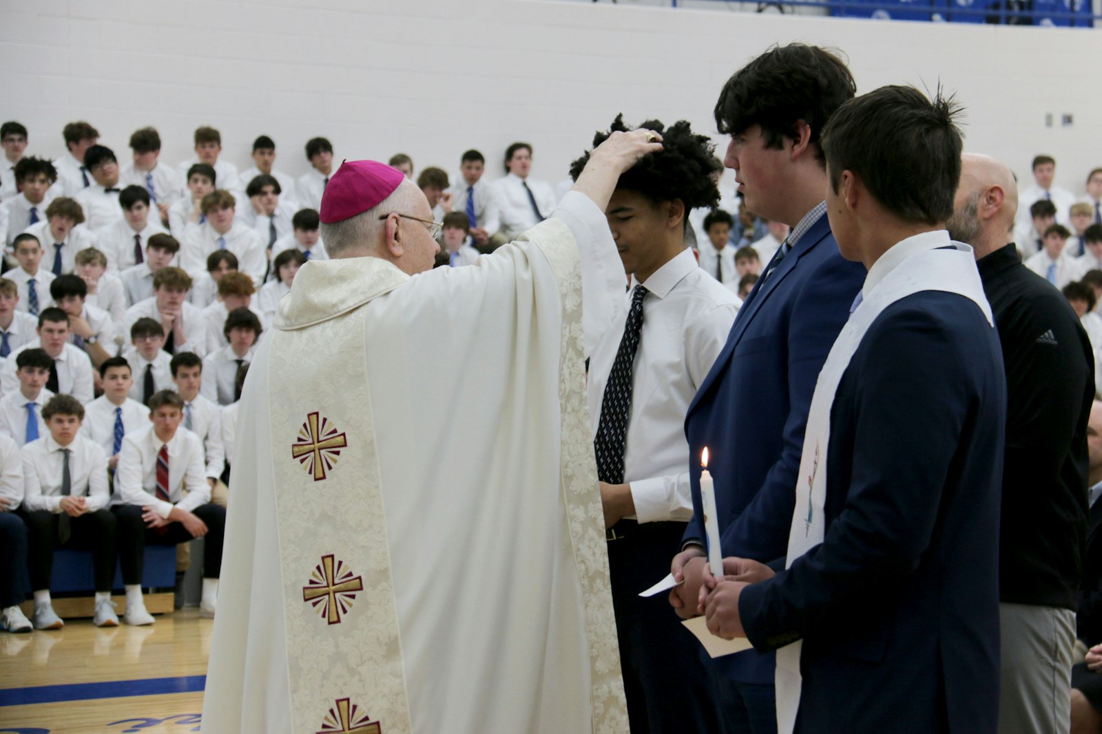 Bishop Hanchon consecrates the heads of the newly confirmed students with holy oil. Although the formation is led by theology teachers, Whitehead believes the young men were drawn to the faith because of the influence of their high school peers.