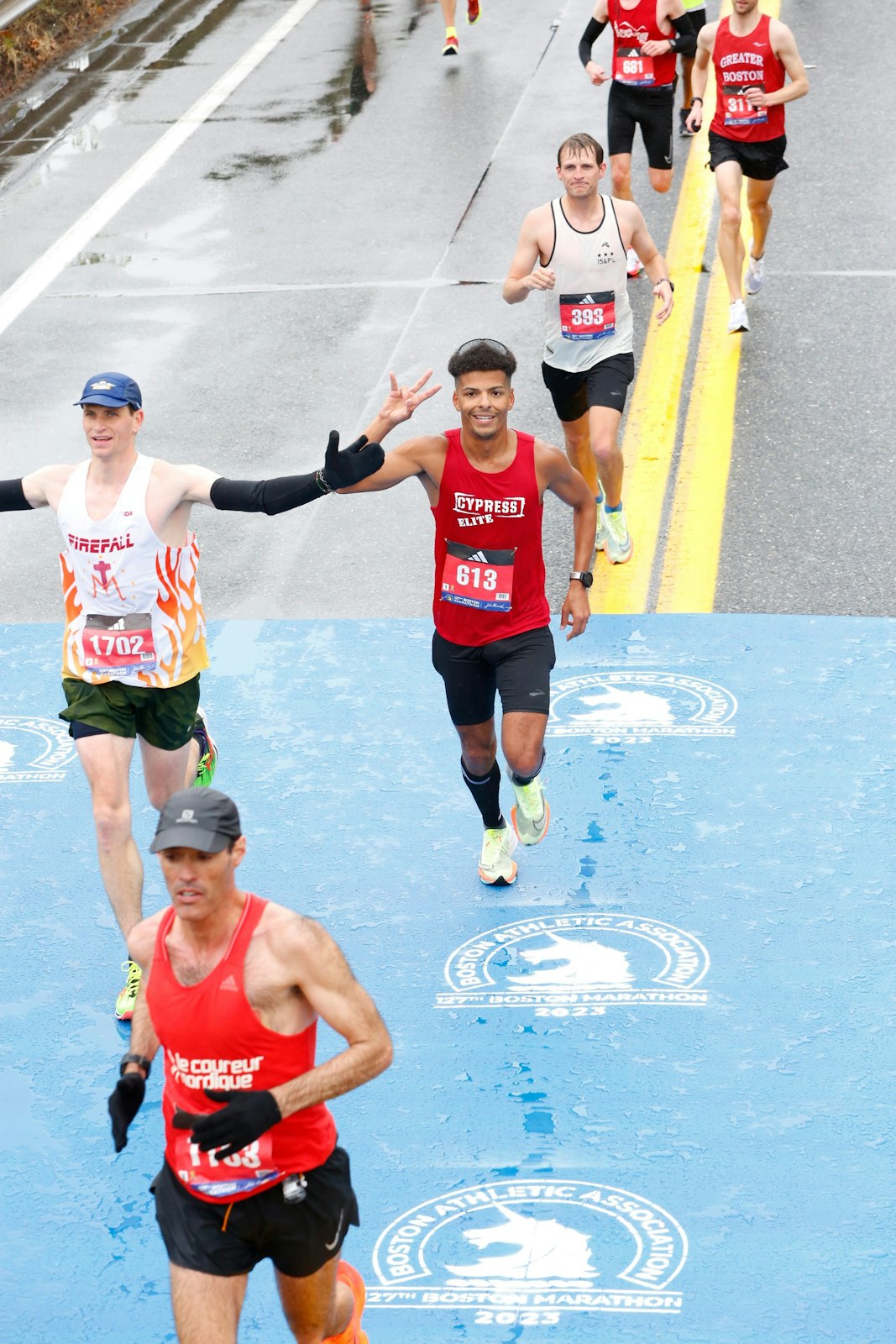 Deacon Seamus Kettner, left, raises his arms to pump up the crowd around the 16-mile mark during the Boston Marathon on April 17. (Courtesy photos)