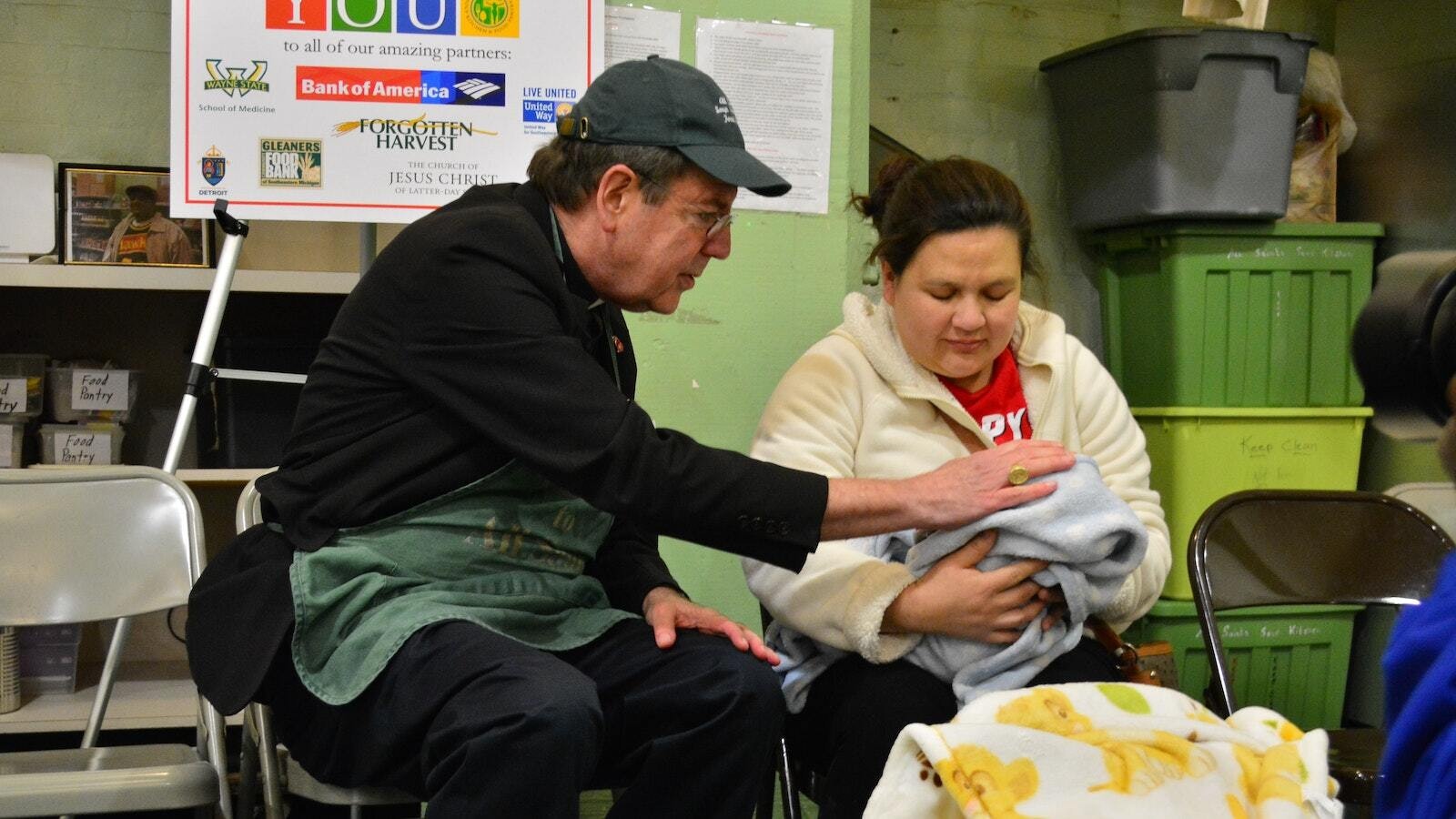 El Arzobispo Vigneron bendice a un bebé recién nacido y a su madre mientras trabaja como voluntario en All Saints Soup Kitchen and Food Pantry en el suroeste de Detroit durante la Cuaresma el 13 de febrero de 2018. (Michael Stechschulte | Foto de archivo de Detroit Catholic)
