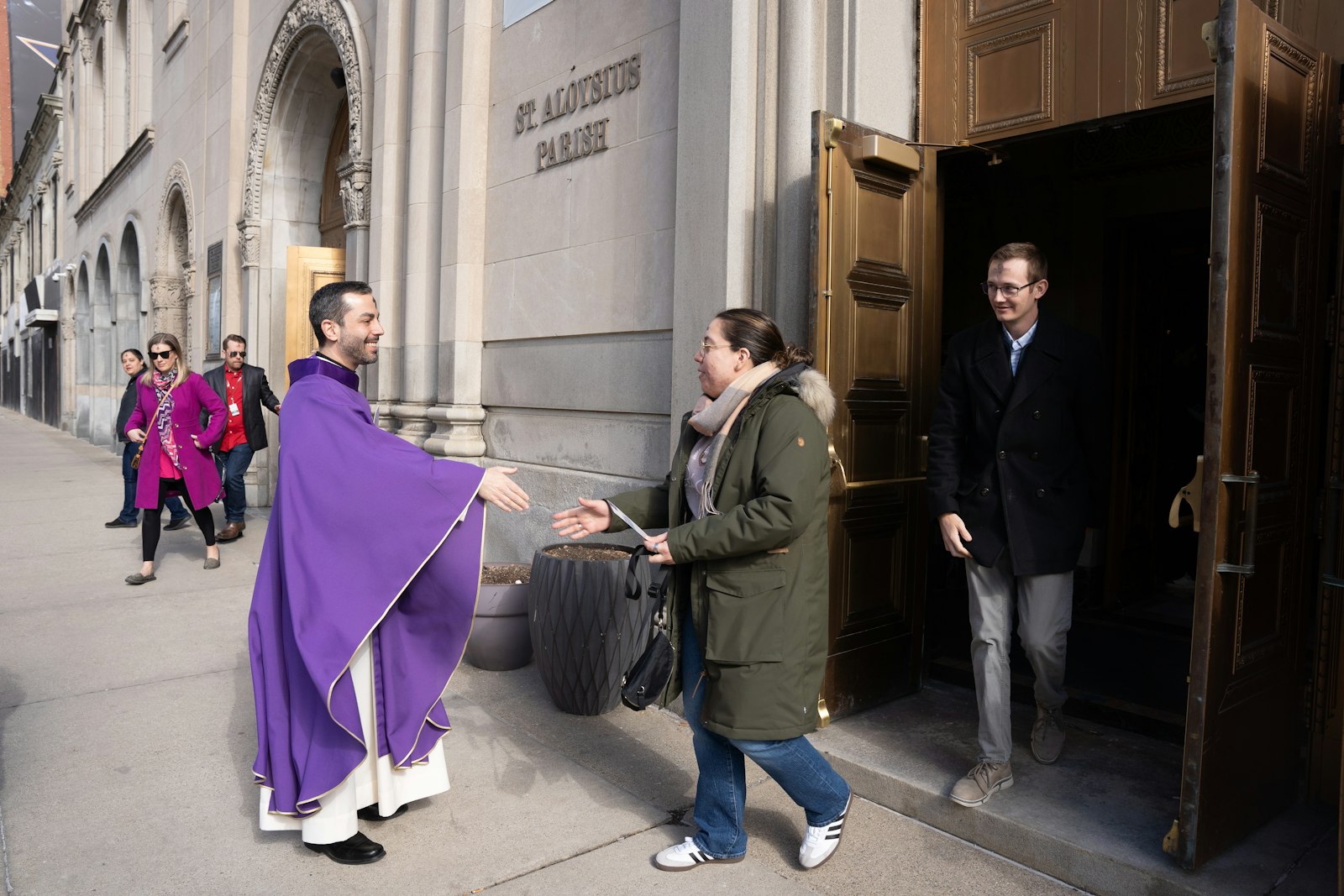 El Padre Mario Amore de la Parroquia de St. Aloysius saluda a los feligreses después de la Misa. El Arzobispo Vigneron desafió a los católicos reunidos el Miércoles de Ceniza a considerar cómo Dios los está llamando a participar en una gran campaña para recuperar el mundo para Cristo.