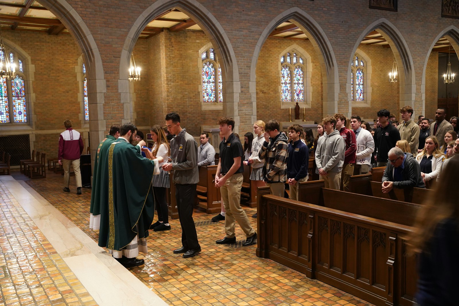 Fr. Jeremy Schupbach distributes Communion during Mass at the St. Sebastian Captains Day at Sacred Heart Major Seminary. Fr. Schupbach told student-athletes their primary task in life is to be close to Jesus.