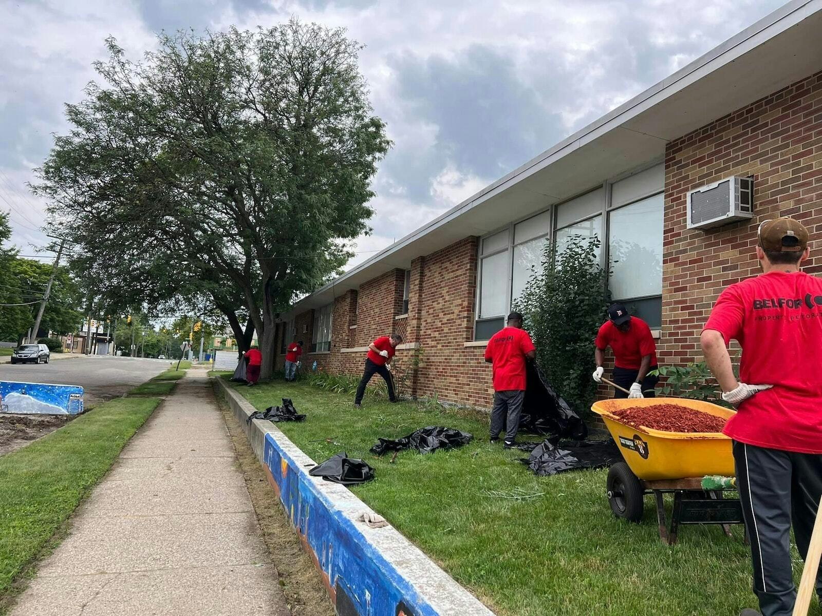 Un grupo de hombres realiza trabajos de jardinería en Christ the King Catholic School de Detroit en julio. Gracias a Better Way Detroit, el exterior de la escuela luce renovado para el inicio del año escolar. (Cortesía de Better Way Detroit)