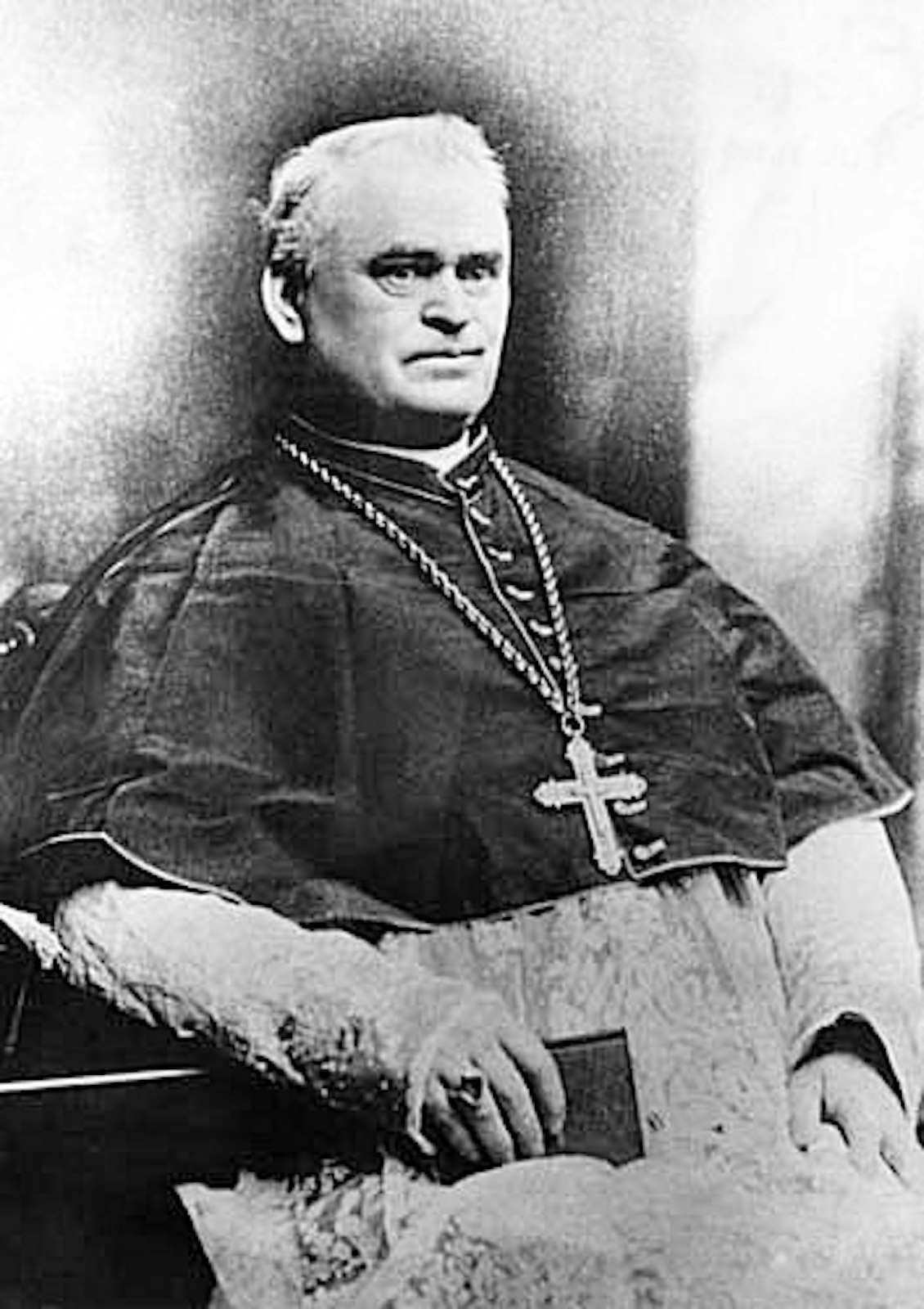 Bishop Patrick Manogue is pictured seated with a Bible in traditional choir dress, cassock and rochet in the 1880s.