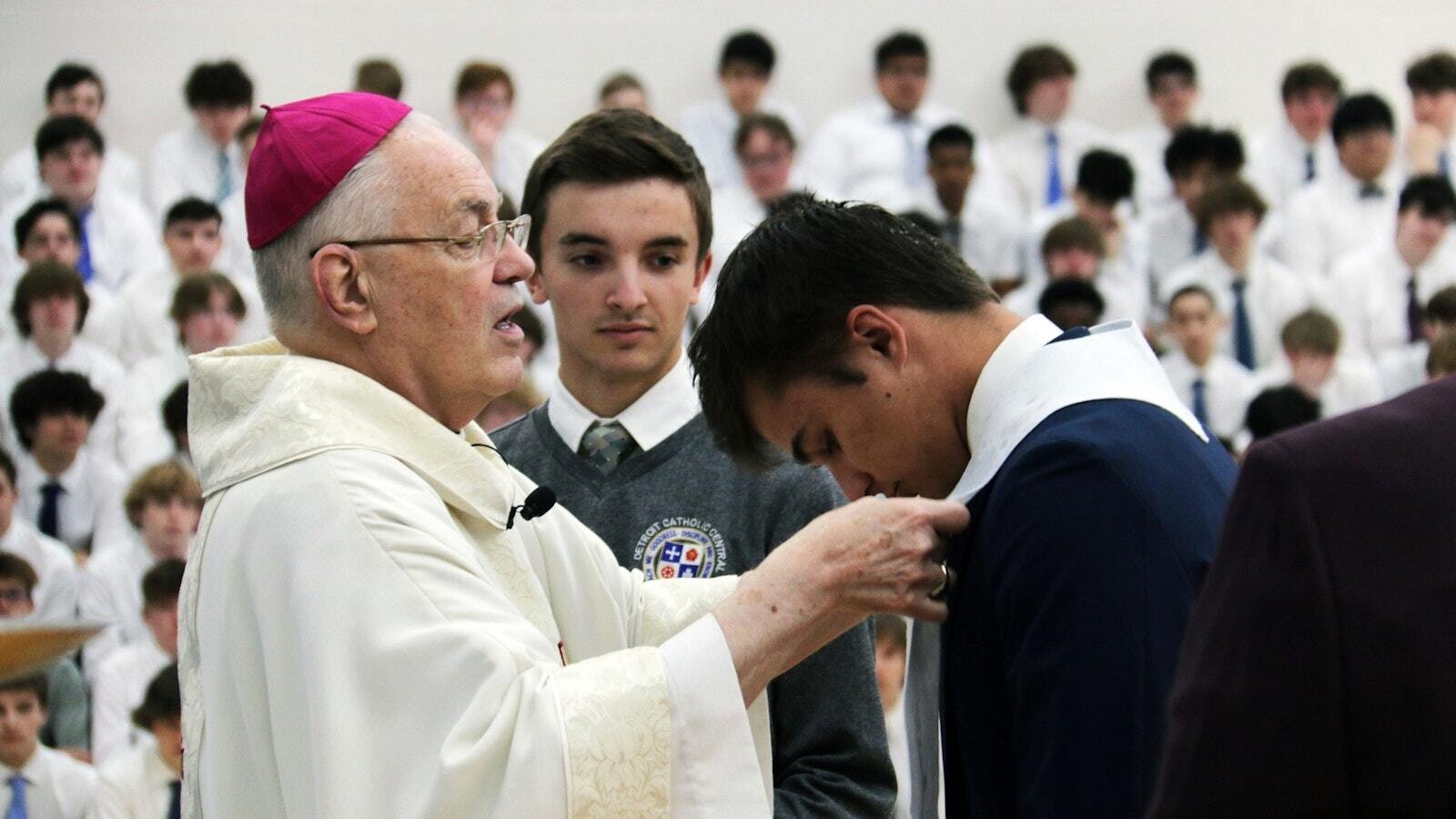 El Obispo Auxiliar de Detroit, Donald F. Hanchon, coloca una estola blanca alrededor del cuello de un estudiante durante una Misa escolar en Catholic Central High School en abril de 2022, en la que cuatro estudiantes completaron sus sacramentos de iniciación. Desde entonces, otros 33 estudiantes de Catholic Central han sido plenamente iniciados en la Iglesia, y 18 más están inscritos este otoño. (Foto de Gabriella Patti | Detroit Catholic)