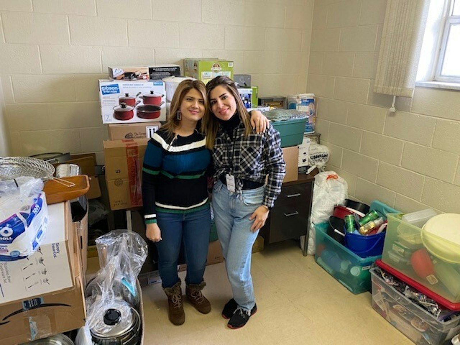 Yasmeen Baban and Baidaa Al-Jashamy of Catholic Charities of Southeast Michigan’s refugee resettlement services stand with supplies collected by St. Irenaeus Parish in Rochester Hills at Catholic Charities’ Royal Oak location. (Photo courtesy of Catholic Charities of Southeast Michigan)