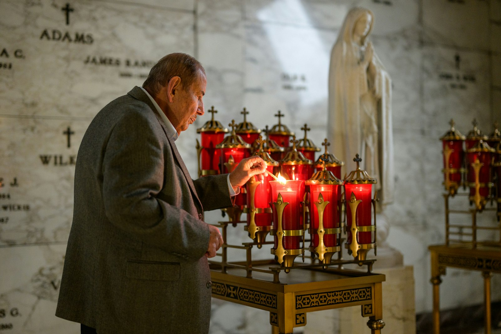 A man lights a votive candle inside the mausoleum at Holy Sepulchre Cemetery in Southfield. (Photo by Valaurian Waller | Detroit Catholic)