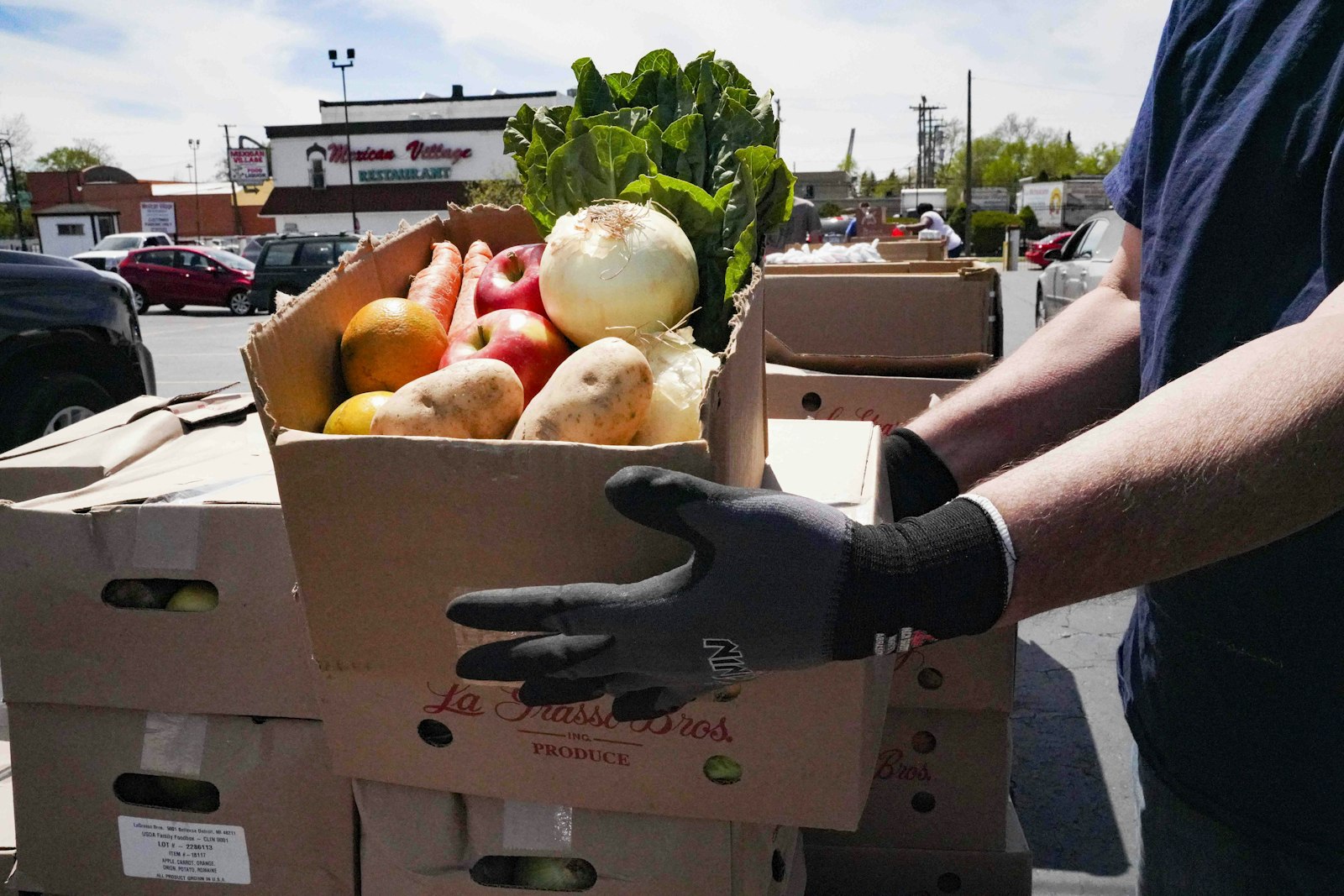 A volunteer carries a box of produce for distribution at the Roberto Clemente Learning Center in Detroit. (Courtesy of Gleaners Community Food Bank)