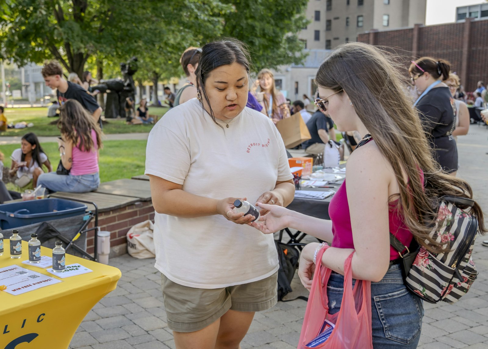 Anna Picasso, left, outreach coordinator for Detroit Catholic Campus Ministry, offers a bottle of holy water to a student at the College for Creative Studies in Detroit. Picasso said the campus ministry team explains to students the purpose of holy water, inviting students to bless their dorms, apartments, cars and study spaces.