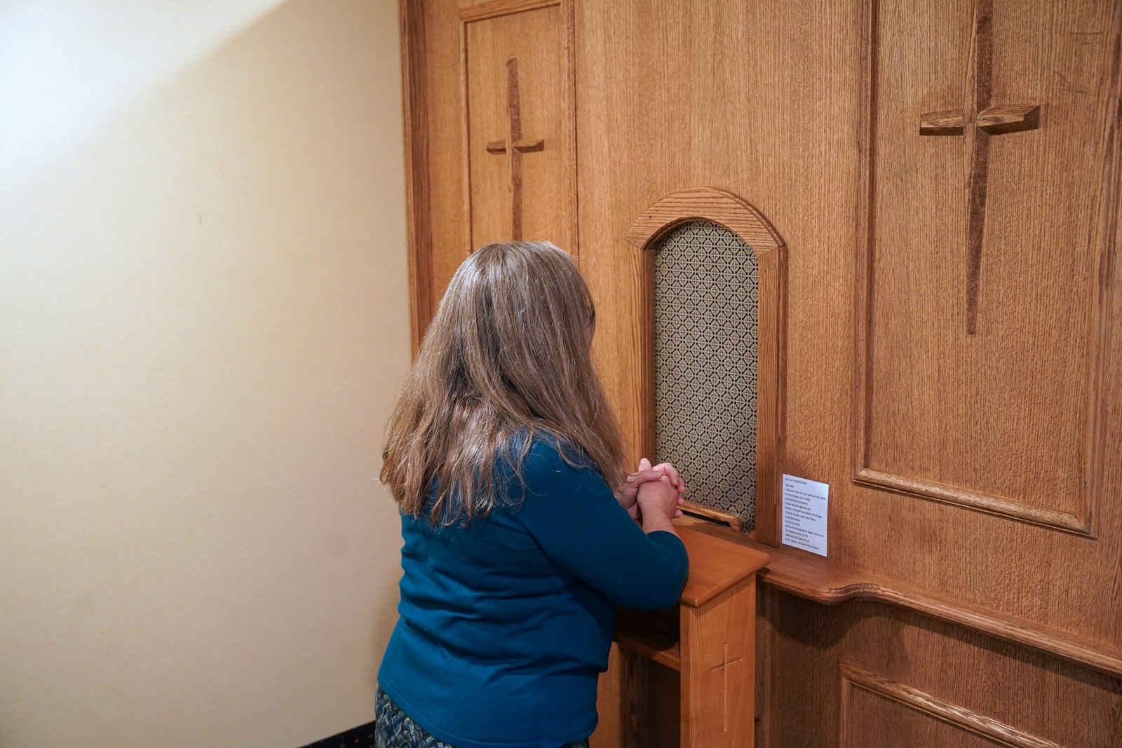 A woman kneels behind the screen at Prince of Peace Parish's new confessional in this staged photo. Fr. Dawson reached out to Tom Oulette, grand knight of Knights of Columbus Council 13362 at St. Fabian Parish in Farmington Hills, to build a new confessional screen that had a more permanent, reverent look.