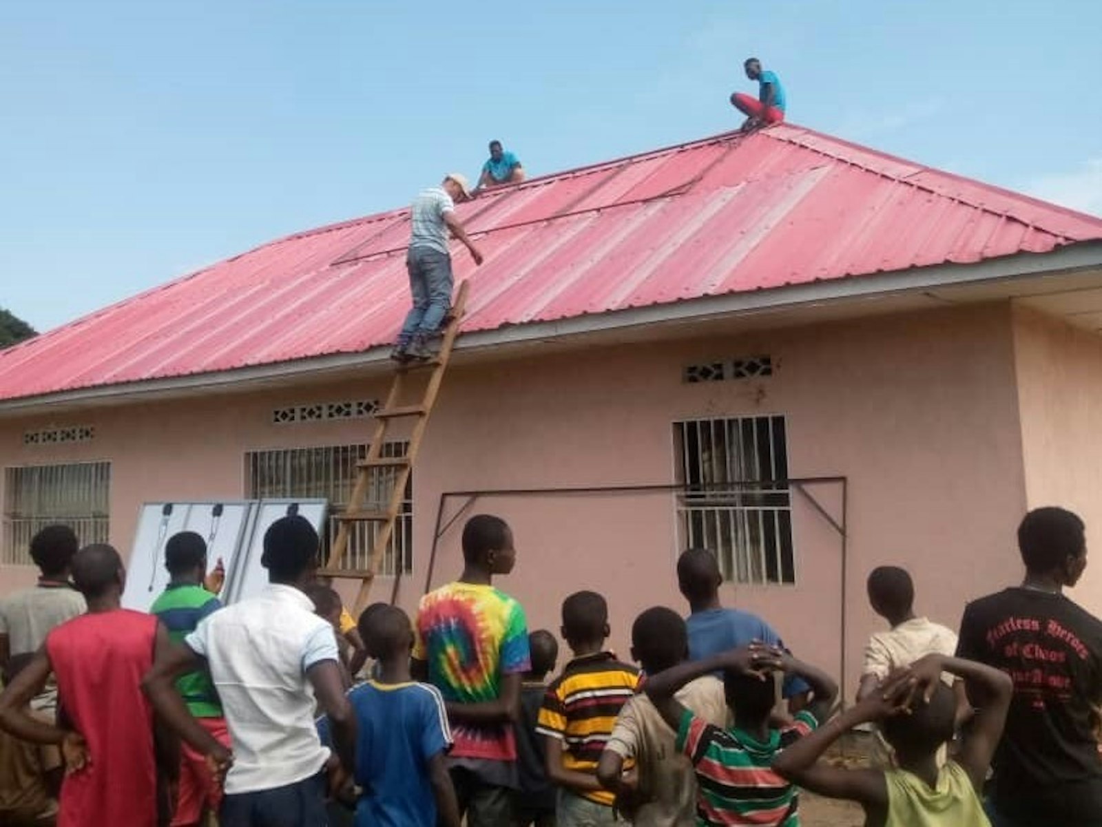 Workers prepare to mount solar panels to the roof of the clinic in January 2021 that would power a well to provide clean water to the town.