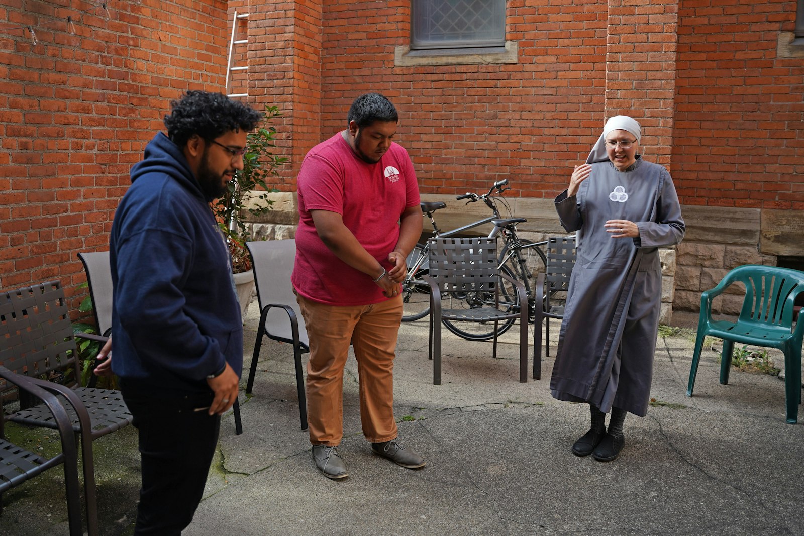 Ricardo Hernandez, left, Daniel Magareno and Sr. Kateri Burbee, SOLT, pray before a meal Sept. 28 as part of Cor Ignis' monthly meeting at the Basilica of Ste. Anne in southwest Detroit.