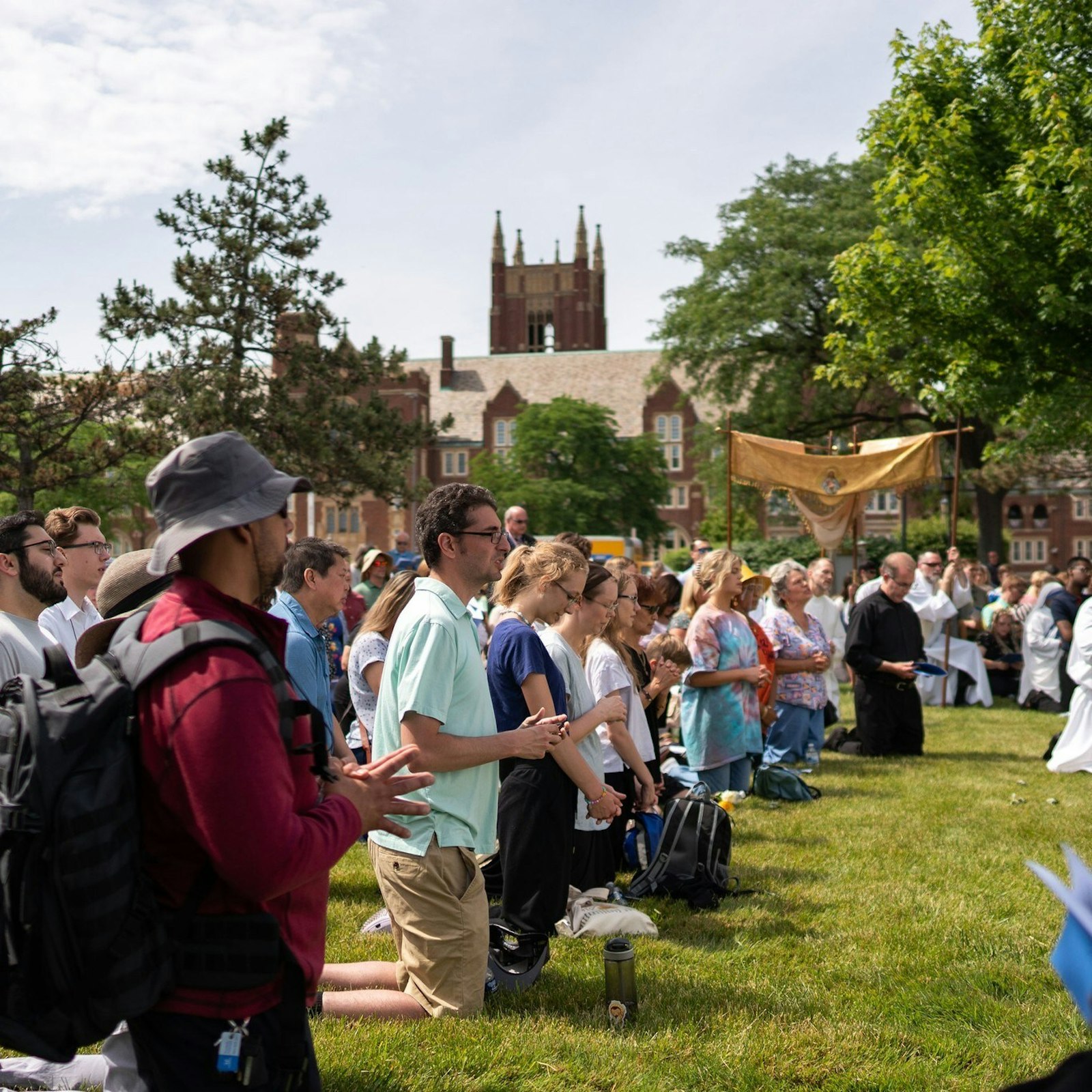 People kneel on the grass at Sacred Heart Major Seminary during benediction following the two-mile Eucharistic procession. (Melanie Reyes | Special to Detroit Catholic)