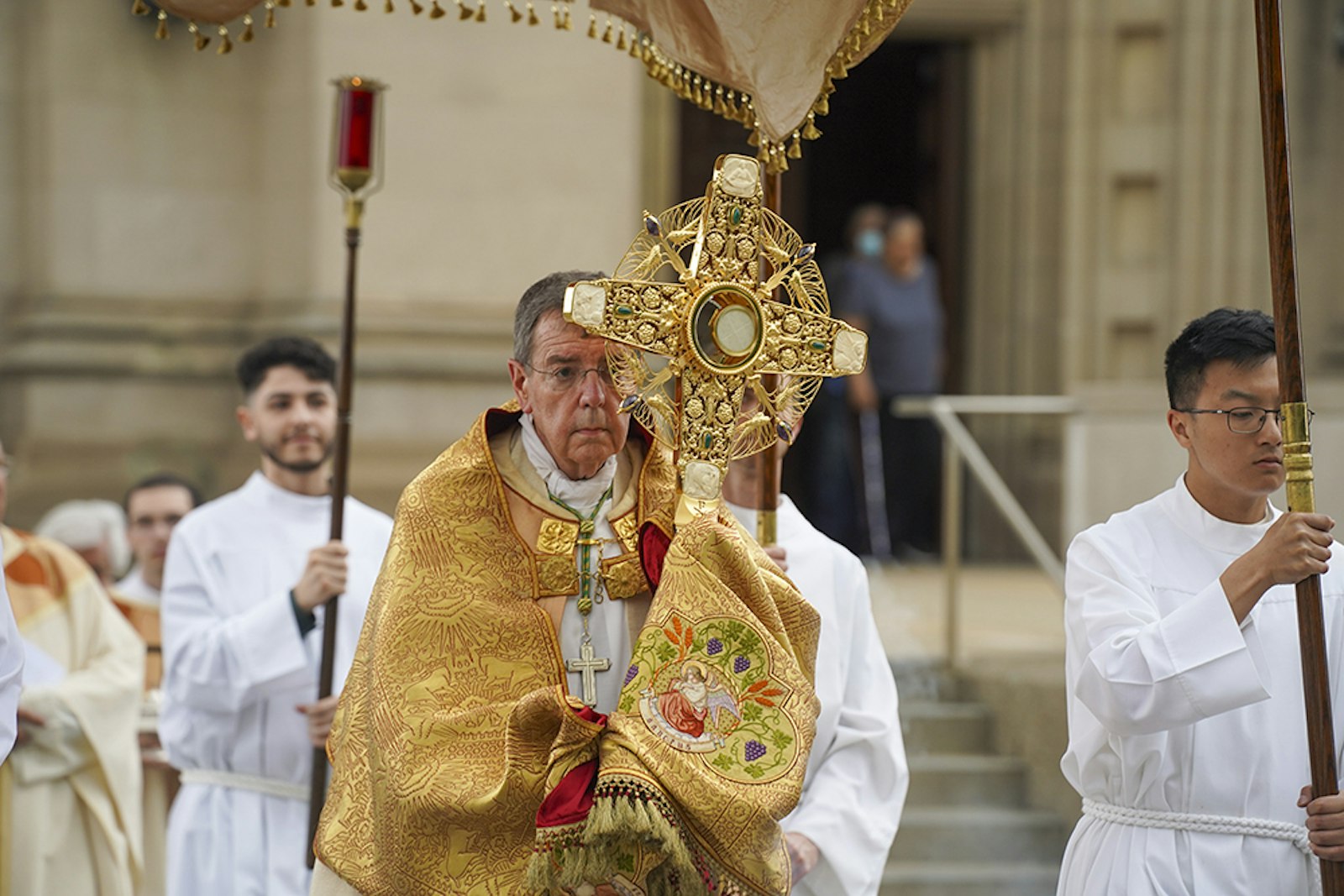 Detroit Archbishop Allen H. Vigneron carries Jesus in the Blessed Sacrament in the monstrance out the front doors of the Cathedral of the Most Blessed Sacrament on June 2 during a Eucharistic procession around the neighborhood in observance of the Solemnity of the Most Holy Body and Blood of Jesus, also known as Corpus Christi. (Photos by Valaurian Waller | Detroit Catholic)