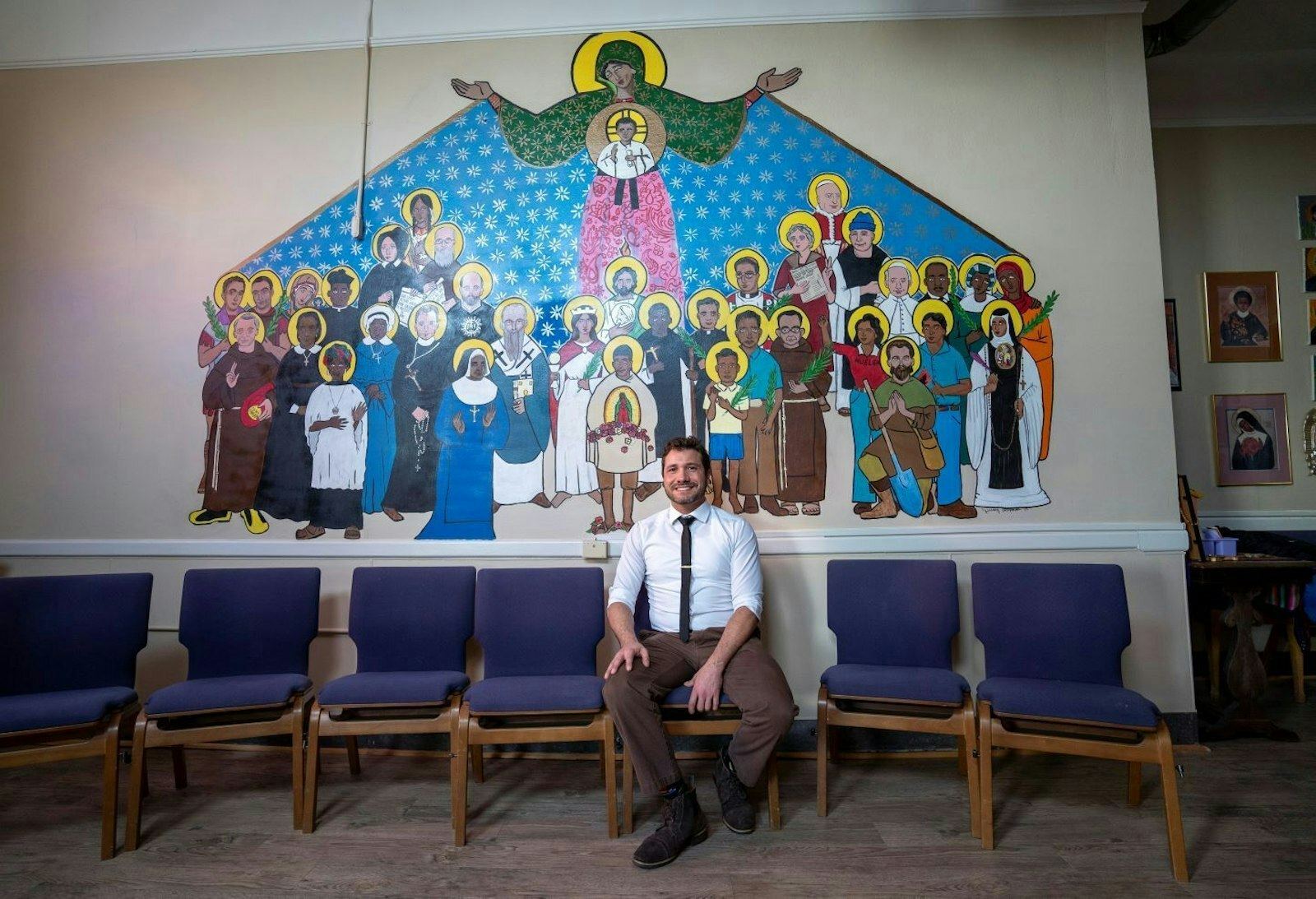 El profesor de teología de Cristo Rey, Jeremy Alexander, pintó el nuevo mural en la capilla del colegio. Está representados María, Jesús y varios santos.