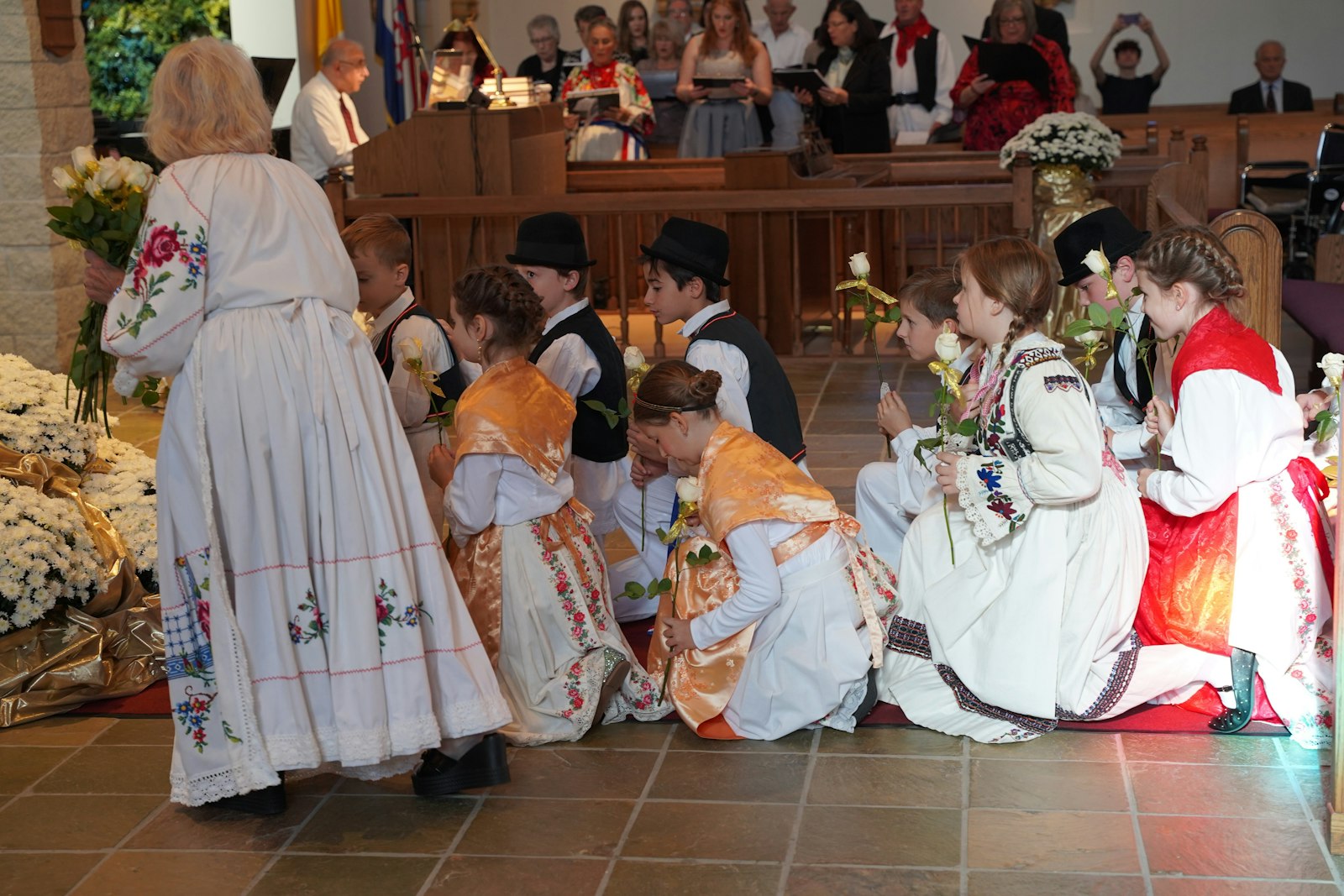 Youth from St. Lucy Croatian Parish, dressed in their traditional dress "Lika" kneel before placing flowers before a statue of Our Lady of Bistricia near the altar of the parish.