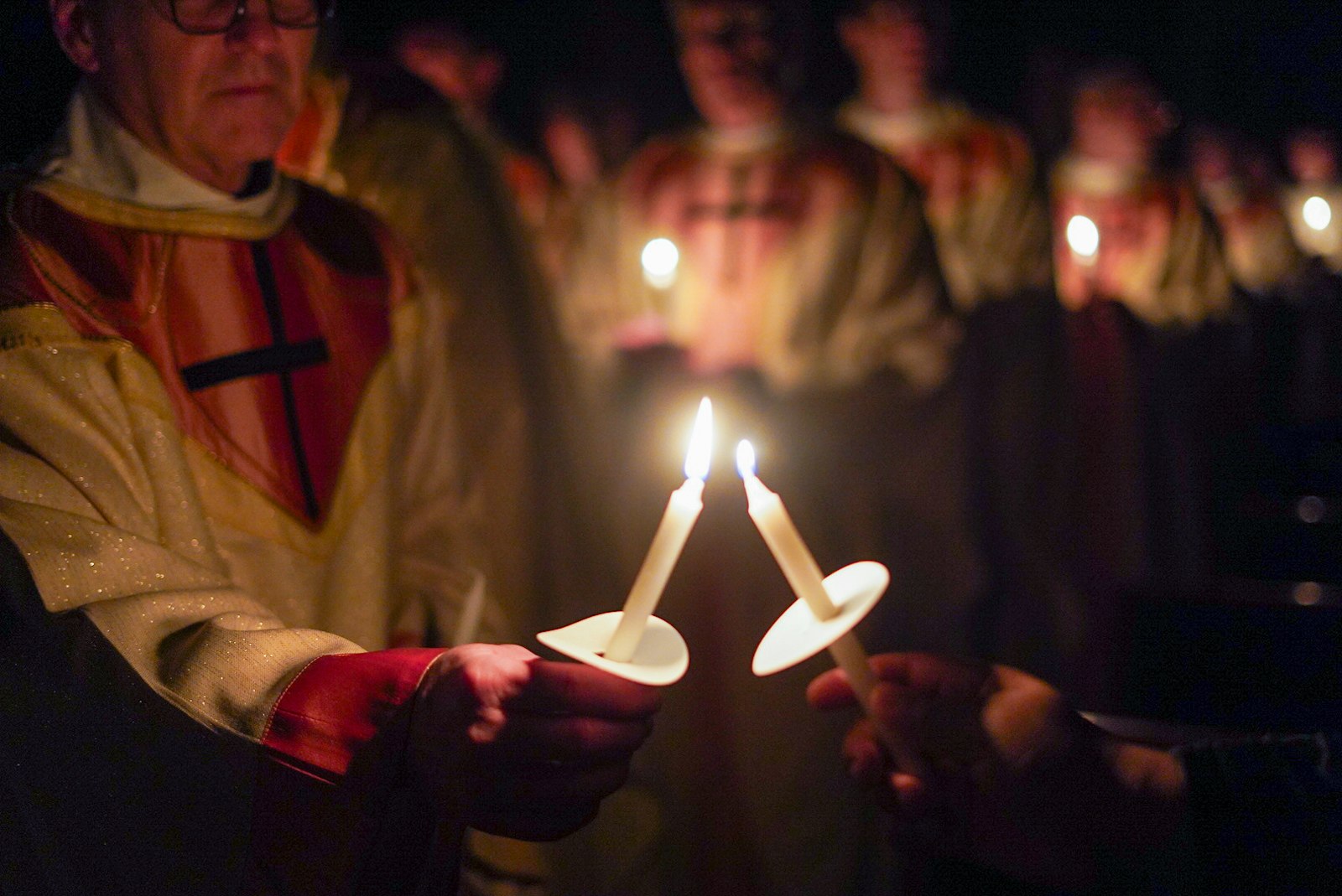 Sacerdotes y diáconos comparten la llama del cirio pascual con los fieles en los bancos de la Cathedral of the Most Blessed Sacrament durante el inicio de la Vigilia Pascual