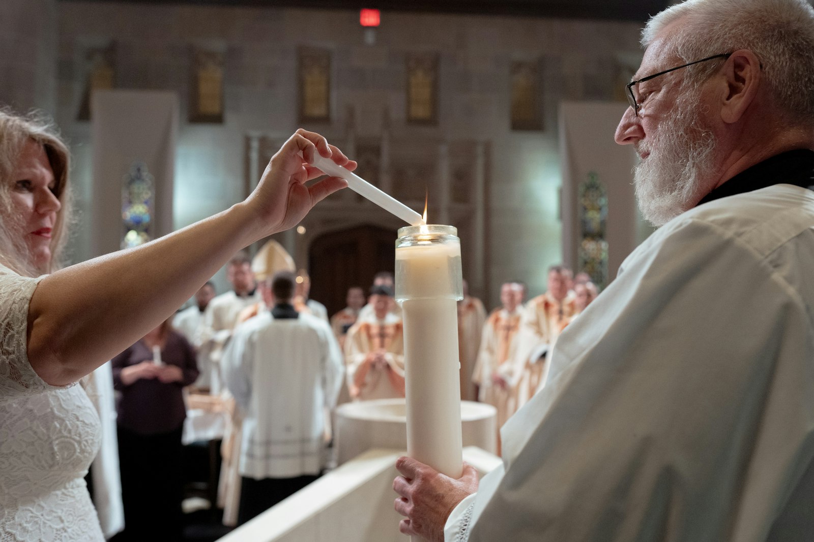 Sponsors, catechists and family members share light from the Easter candle after six people were baptized. Four more received confirmation and their first Communions along with those who were newly baptized.