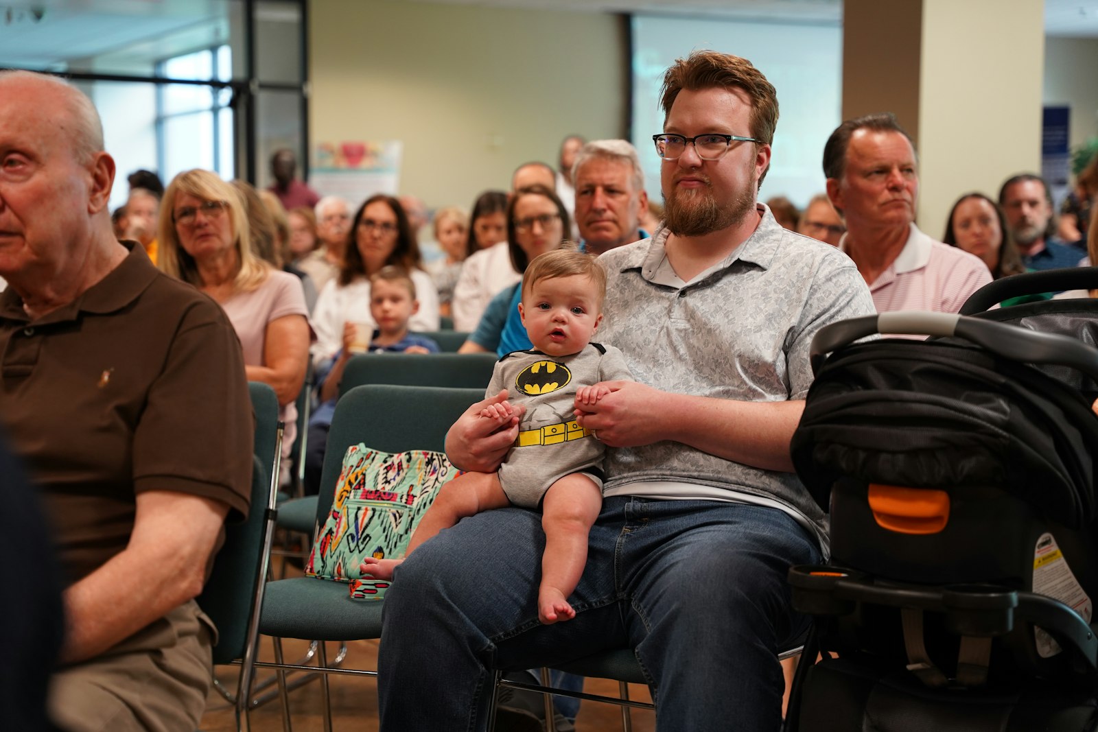 A man holds a baby while listening to a panel discussion at Our Lady of Good Counsel Parish in Plymouth on Sept. 13 on the implications of the proposed "Reproductive Freedom for All" amendment, which critics say would result in the "most extreme abortion law in the country" should it pass on Nov. 8.