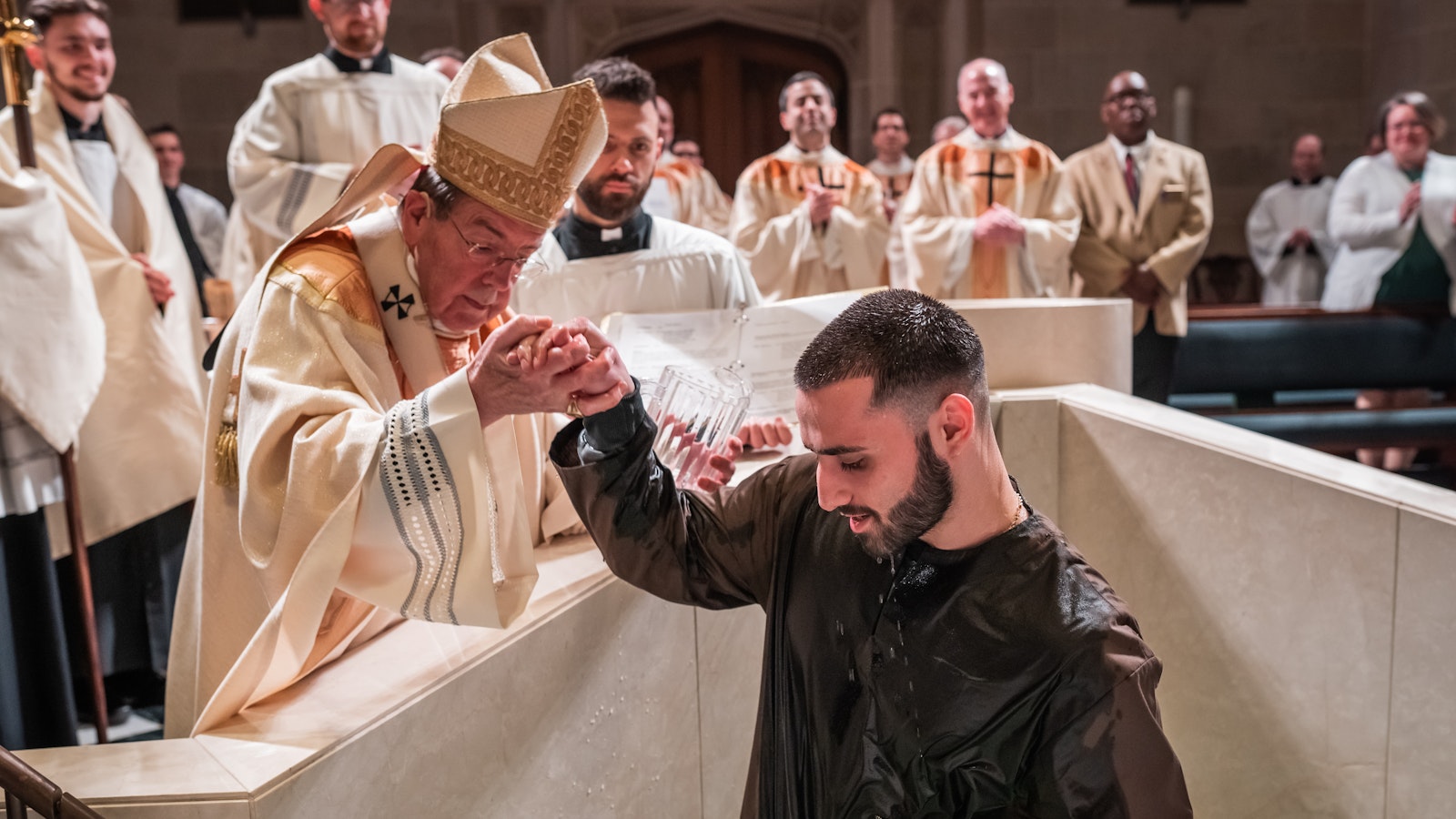 Archbishop Vigneron helps a catechumen out of the baptismal waters after baptizing him during the Easter Vigil on April 8, 2023, at the Cathedral of the Most Blessed Sacrament. (Valaurian Waller | Detroit Catholic)