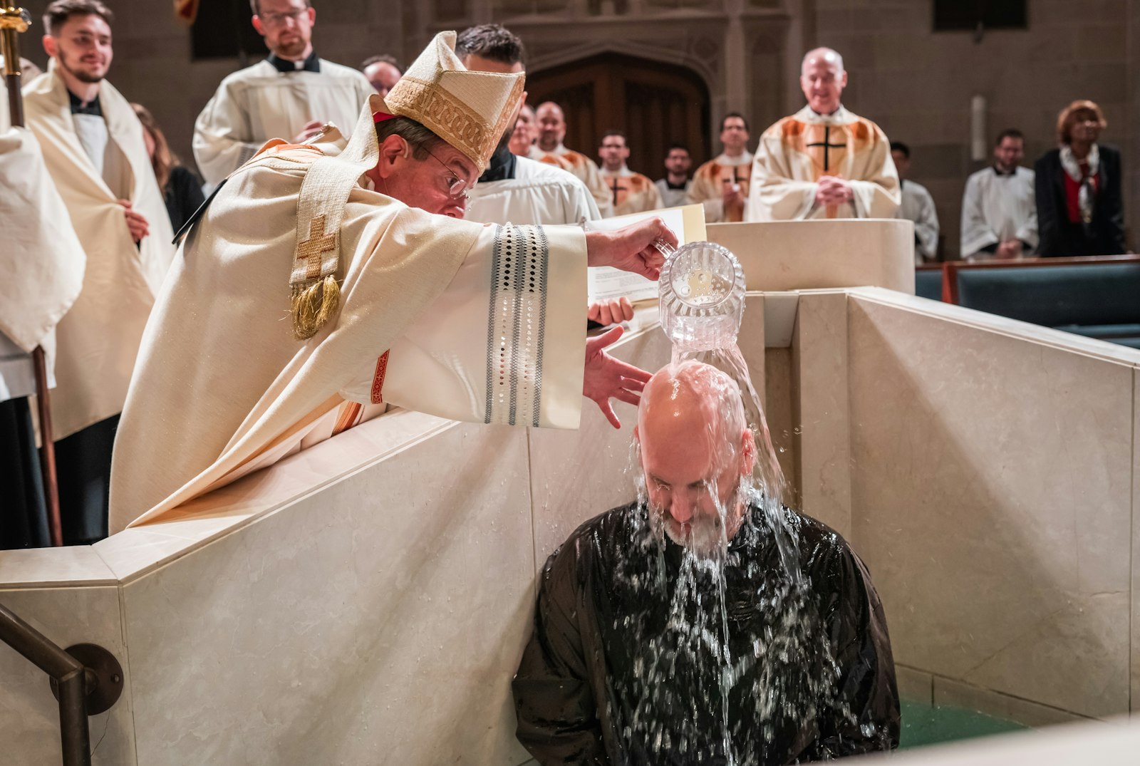 Archbishop Vigneron pours water over Brian Mull, baptizing him into the Catholic faith during the Easter vigil. Mull joined OCIA in November 2022, but his journey toward becoming Catholic really began two years ago when he was hired by Blue Rock Technologies to work as an on-site technician at the Archdiocese of Detroit’s Chancery in downtown Detroit.